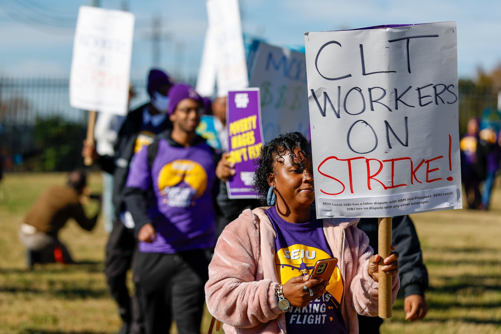 Airport workers wave signs as they march in front of the Charlotte Douglas International Airport in Charlotte, N.C., Monday, Nov. 25, 2024. (AP Photo/Nell Redmond)