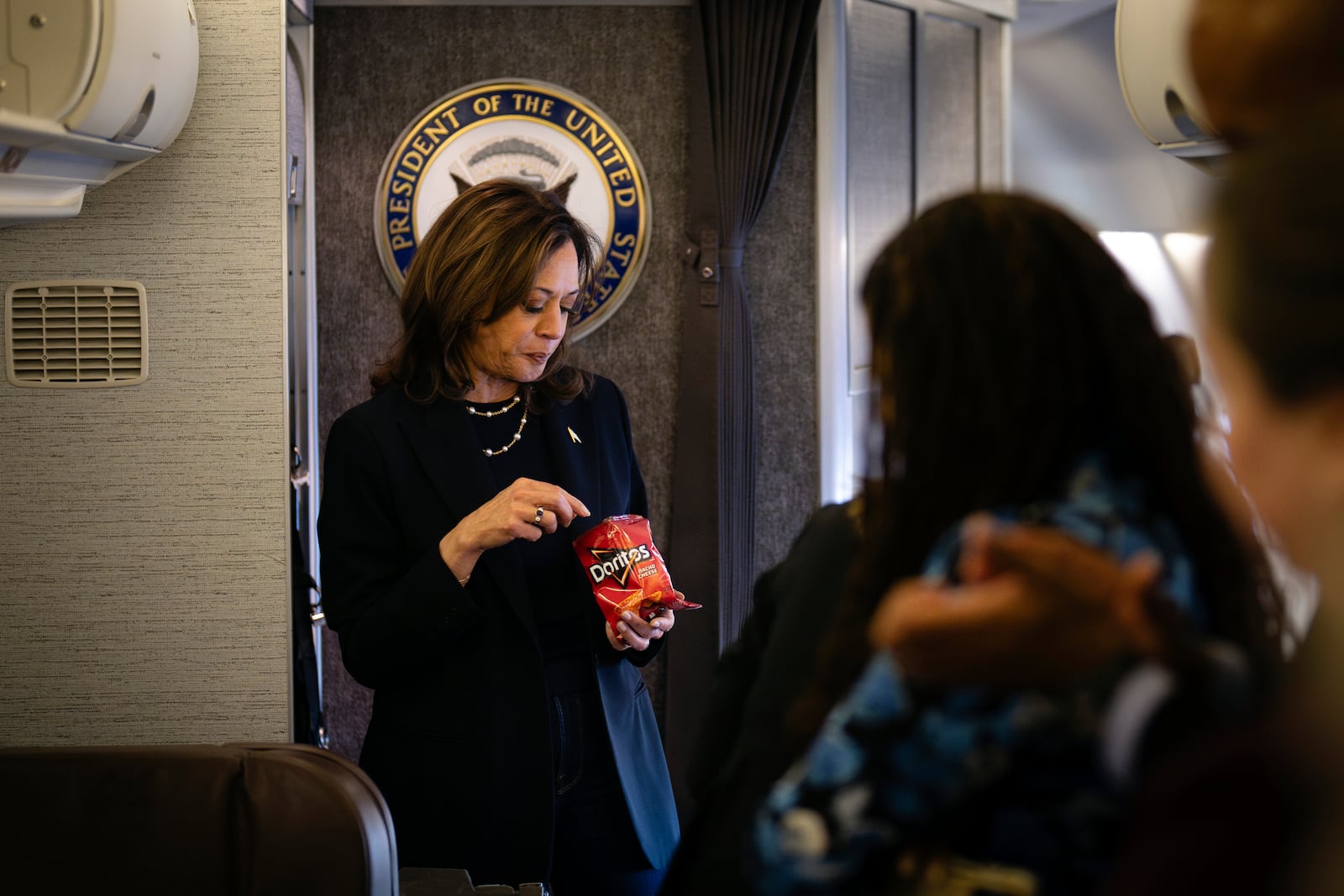 Democratic presidential nominee Vice President Kamala Harris eats Doritos and thanks senior staff aboard Air Force Two in Philadelphia, Sunday, Oct. 27, 2024. (Erin Schaff//The New York Times via AP, Pool)