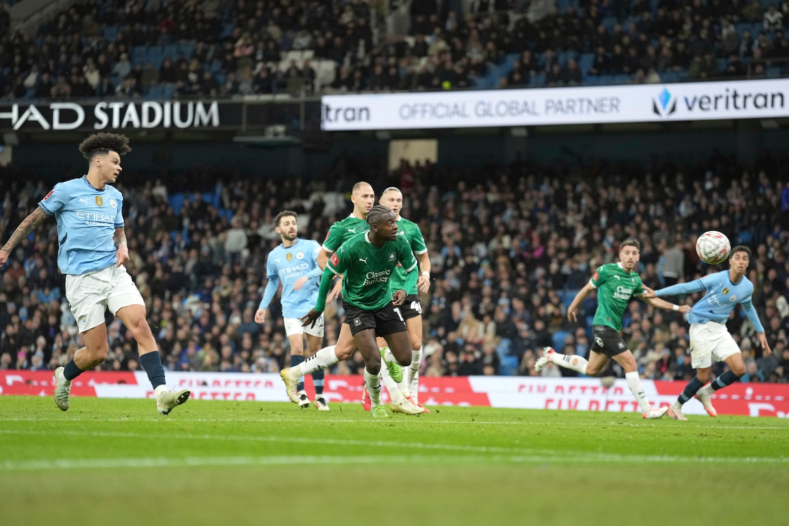 Manchester's Nico O'Reilly, left, scores his side's opening goal during the English FA Cup soccer match between Manchester City and Plymouth Argyle at Etihad Stadium, Manchester, England, Saturday, March 1, 2025. (AP Photo/Jon Super)