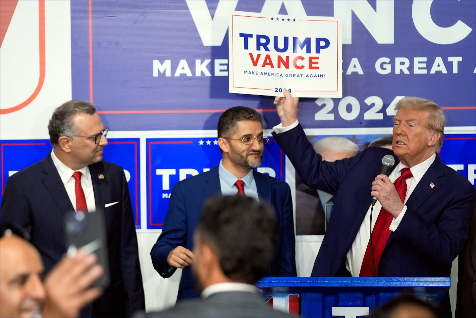 Republican presidential nominee former President Donald Trump speaks as Hamtranck Mayor Amer Ghalib, center, and Massad Boulos, left, listen at a campaign office, Friday, Oct. 18, 2024, in Hamtranck, Mich. (AP Photo/Evan Vucci)