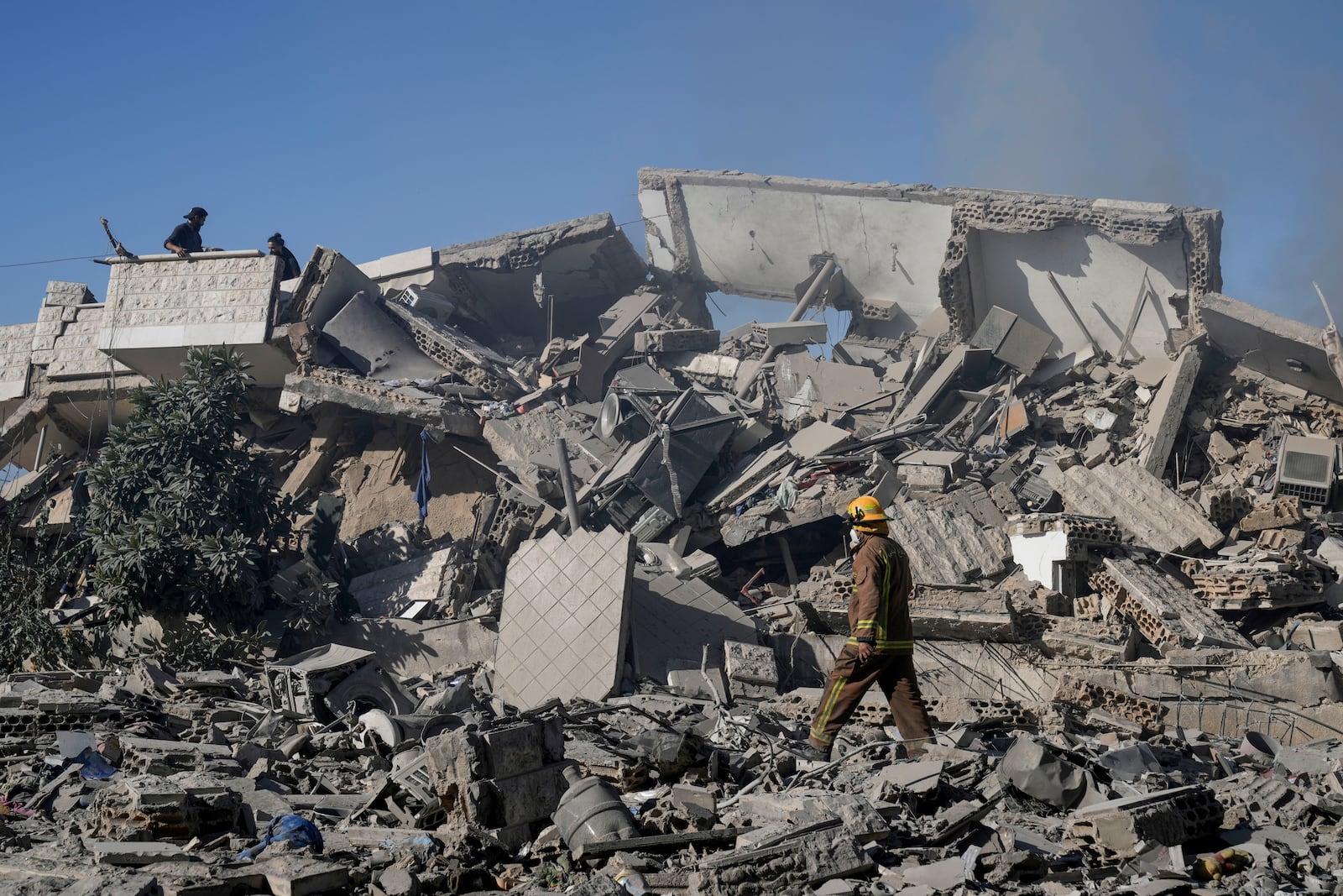 A civil defense worker and civilians check a building that collapsed after it was hit in an Israeli airstrike in Hadath, south of Beirut, Lebanon, Sunday, Nov. 17, 2024. (AP Photo/Bilal Hussein)