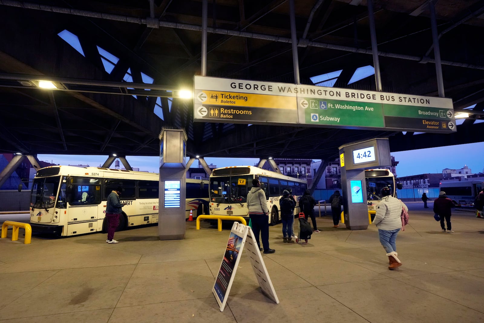 Communters wait for buses at the George Washington Bridge Bus Station in New York, Friday, Dec. 6, 2024, where the gunman fleeing Wednesday's shooting of UnitedHealthcare CEO Brian Thompson took a taxi to, according to surveillance video. (AP Photo/Richard Drew)