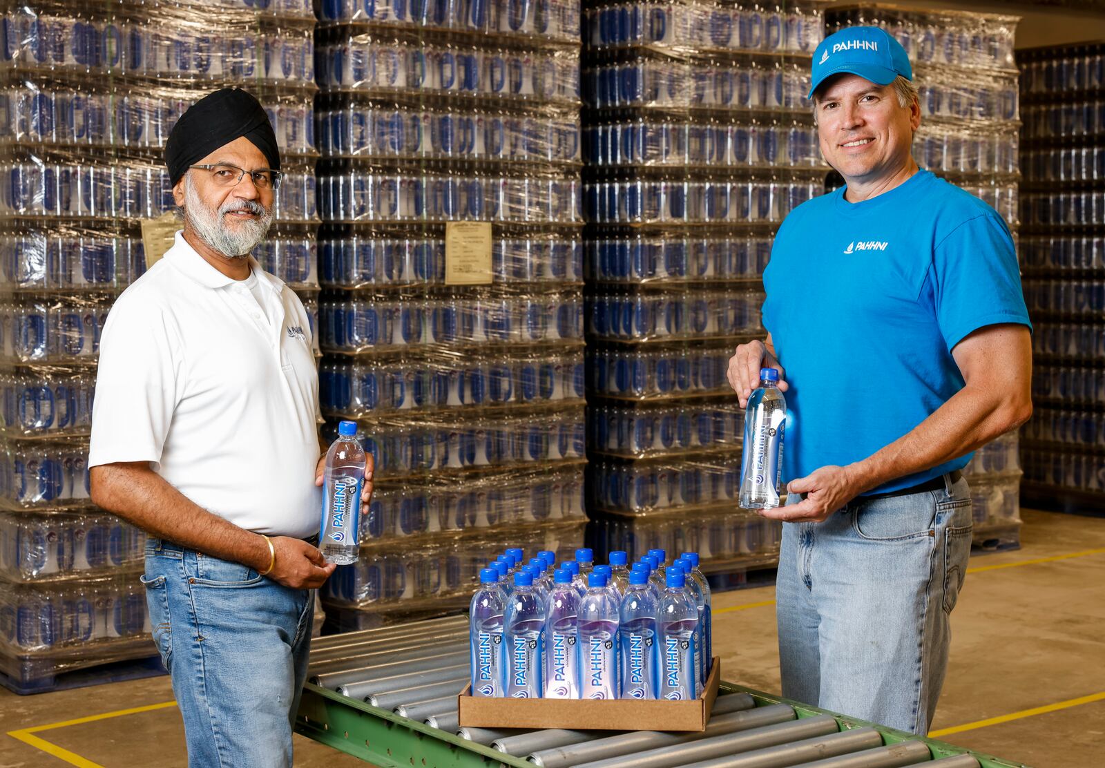 Dr. Satinder Bharaj, PhD, left, and Erik Loomis, co-founders of Pahhni High pH Alkaline Water, have started bottling their products in the Third and Dayton building in Hamilton. NICK GRAHAM/STAFF