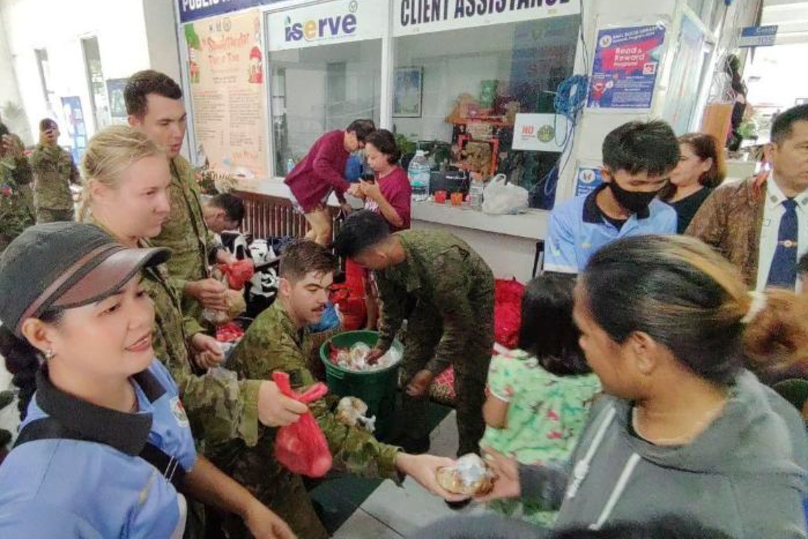 In this handout photo provided by the 9th Infantry Division, Philippine Army, troopers from the 9th Infantry "Spear" Division (9ID) and a contingent from the Australian Army distribute food packs to evacuees affected by Tropical Storm Trami, locally named Kristine, at Naga city, Camarines Sur province, Philippines on Thursday Oct. 24, 2024. (9th Infantry Division, Philippine Army via AP)