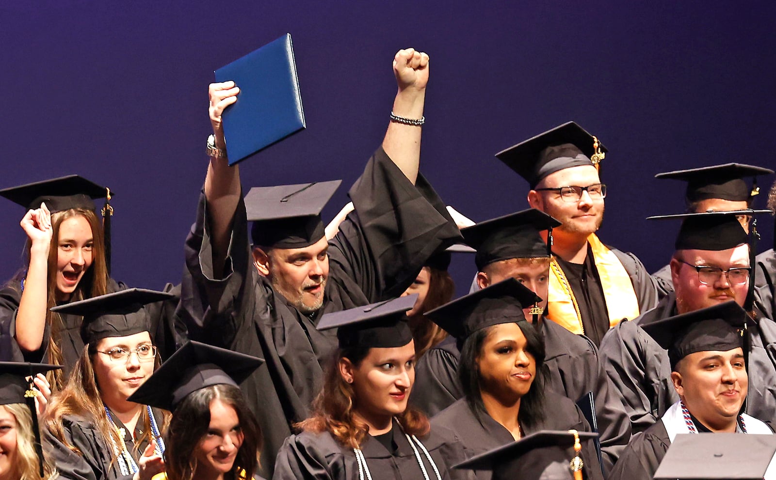 A Clark State College graduate raises his diploma as he celebrates at the conclusion of the school's commencement ceremony Saturday, May 11, 2024. Clark State saw a 15% increase in tuition this fall compared to last year. BILL LACKEY/STAFF