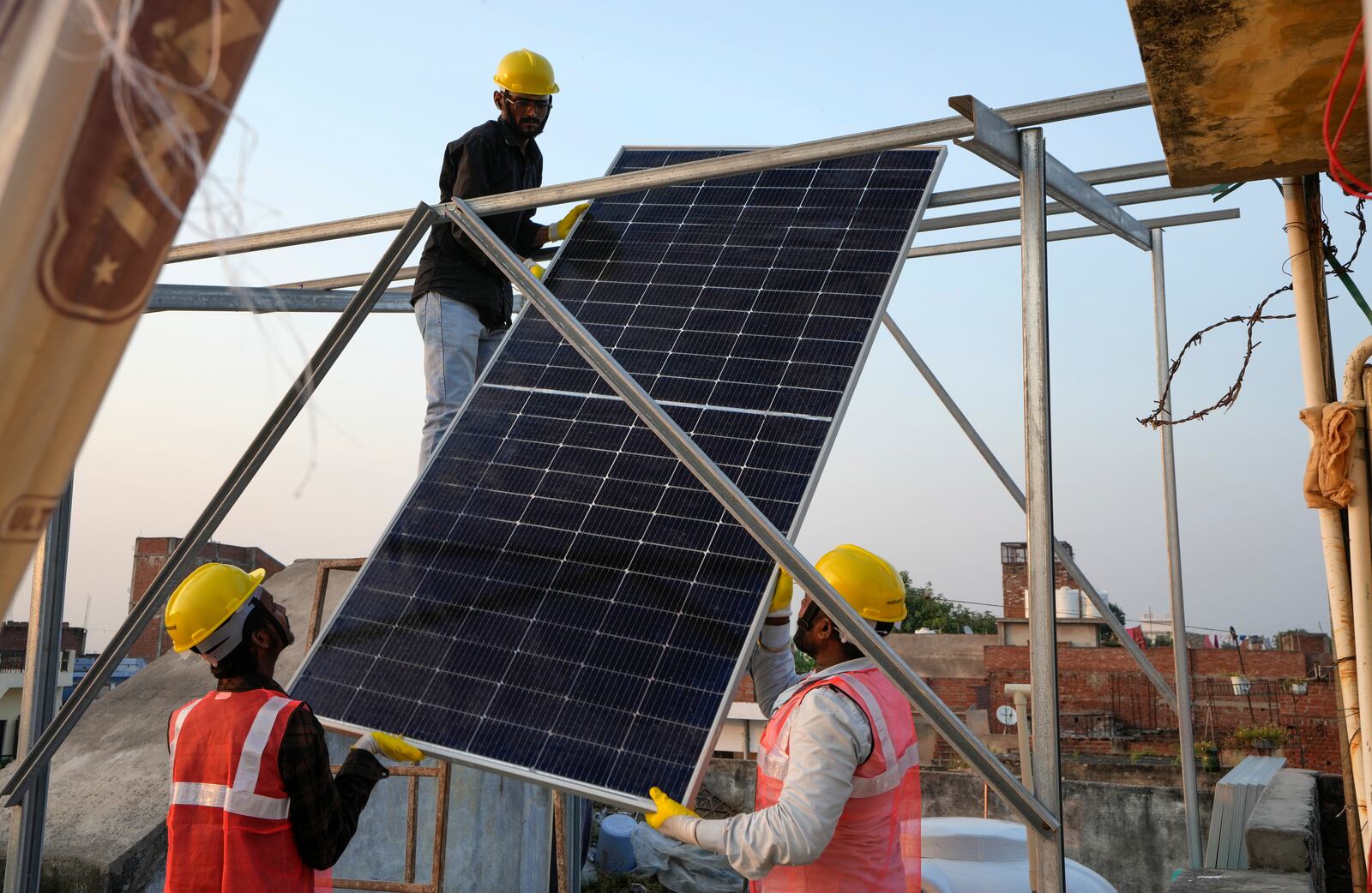 FILE - Solar installers work on a rooftop system at a home in Prayagraj, India, Oct. 14, 2024. (AP Photo/Rajesh Kumar Singh, File)