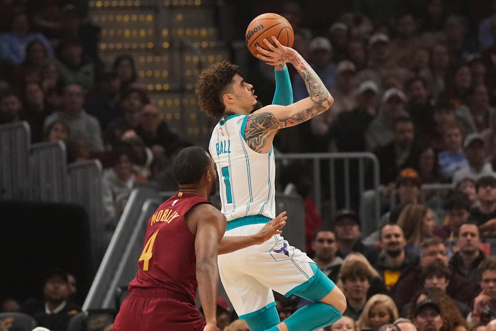 Charlotte Hornets guard LaMelo Ball (1) shoots in front of Cleveland Cavaliers forward Evan Mobley (4) in the first half of an NBA basketball game, Sunday, Jan. 5, 2025, in Cleveland. (AP Photo/Sue Ogrocki)