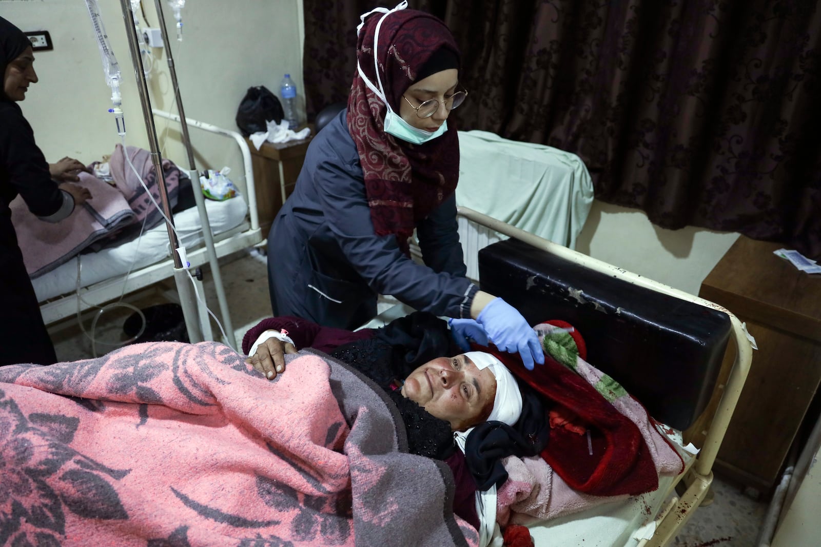 A nurse attends to an injured woman in Idlib, Syria, Sunday Dec. 1, 2024. Government airstrikes in Idlib killed at least three civilians, including two children, and wounded 11 others, said the Syrian Civil Defense, known as the White Helmets, which operates in opposition-held areas. (AP Photo/Omar Albam)