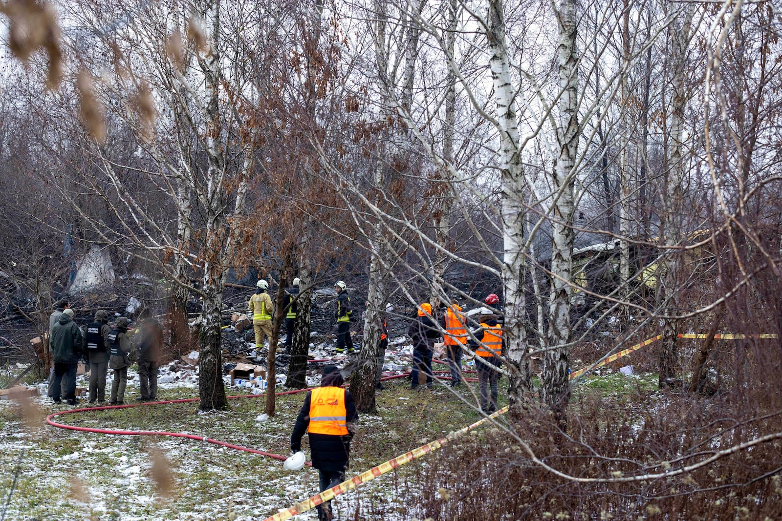 Lithuanian Emergency Ministry employees work near the place where a DHL cargo plane crashed into a house near the Lithuanian capital Vilnius, Lithuania, Monday, Nov. 25, 2024. (AP Photo/Mindaugas Kulbis)