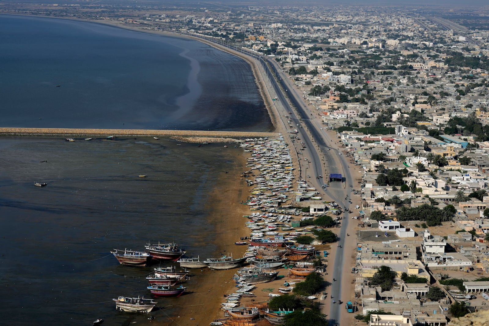 Fishers' boats are docked along the beach next to a new built highway in Gwadar, Pakistan, Tuesday, Jan. 14, 2025. (AP Photo/Anjum Naveed)