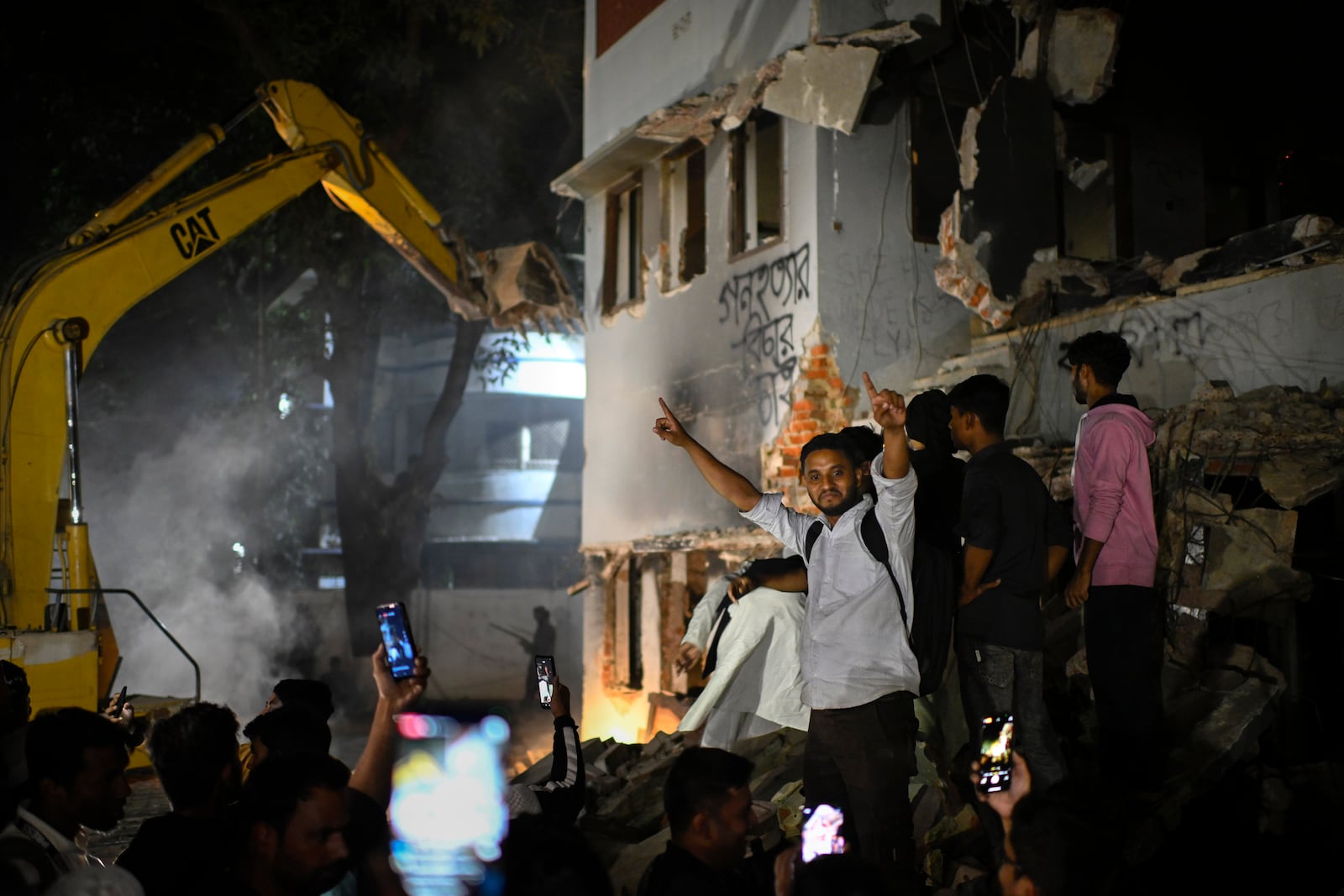 People watch as protesters use heavy machinery to demolish the residence of Sheikh Mujibur Rahman, Bangladesh's former leader and the father of the country's ousted Prime Minister Sheikh Hasina, at Dhanmondi, in Dhaka, Bangladesh, early Thursday, Feb. 6, 2025. (AP Photo/Mahmud Hossain Opu)