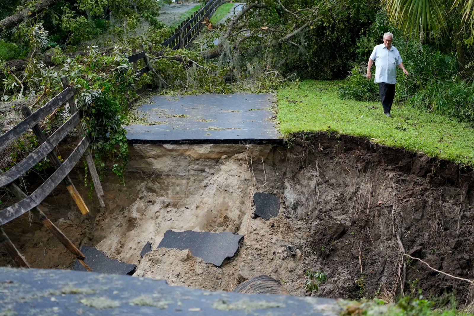 Del Ockey, a seasonal Florida resident from Canada, walks near the damaged bridge from Hurricane Milton, that leads onto his property, Friday, Oct. 11, 2024, in Riverview, Fla. (AP Photo/Julio Cortez)