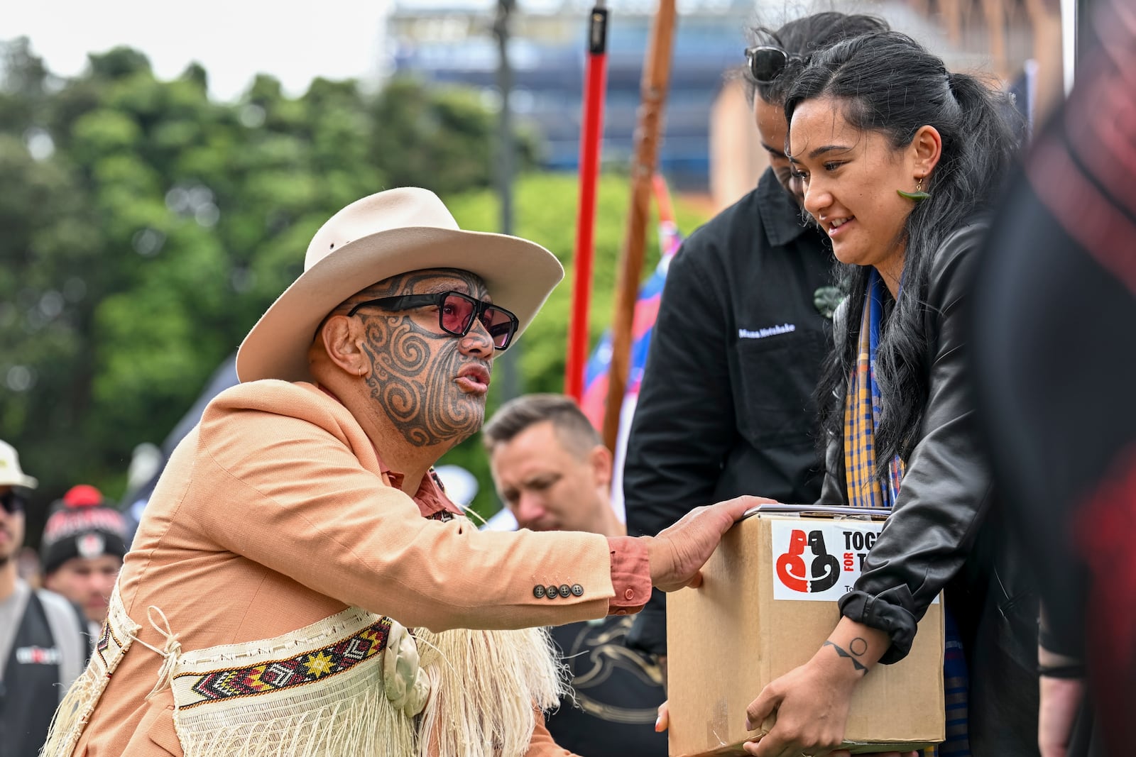 A petition is delivered to Member of Parliament Rawiri Waititi, left, outside New Zealand's parliament during a protest against a proposed law that would redefine the country's founding agreement between Indigenous Māori and the British Crown, in Wellington Tuesday, Nov. 19, 2024. (AP Photo/Mark Tantrum)