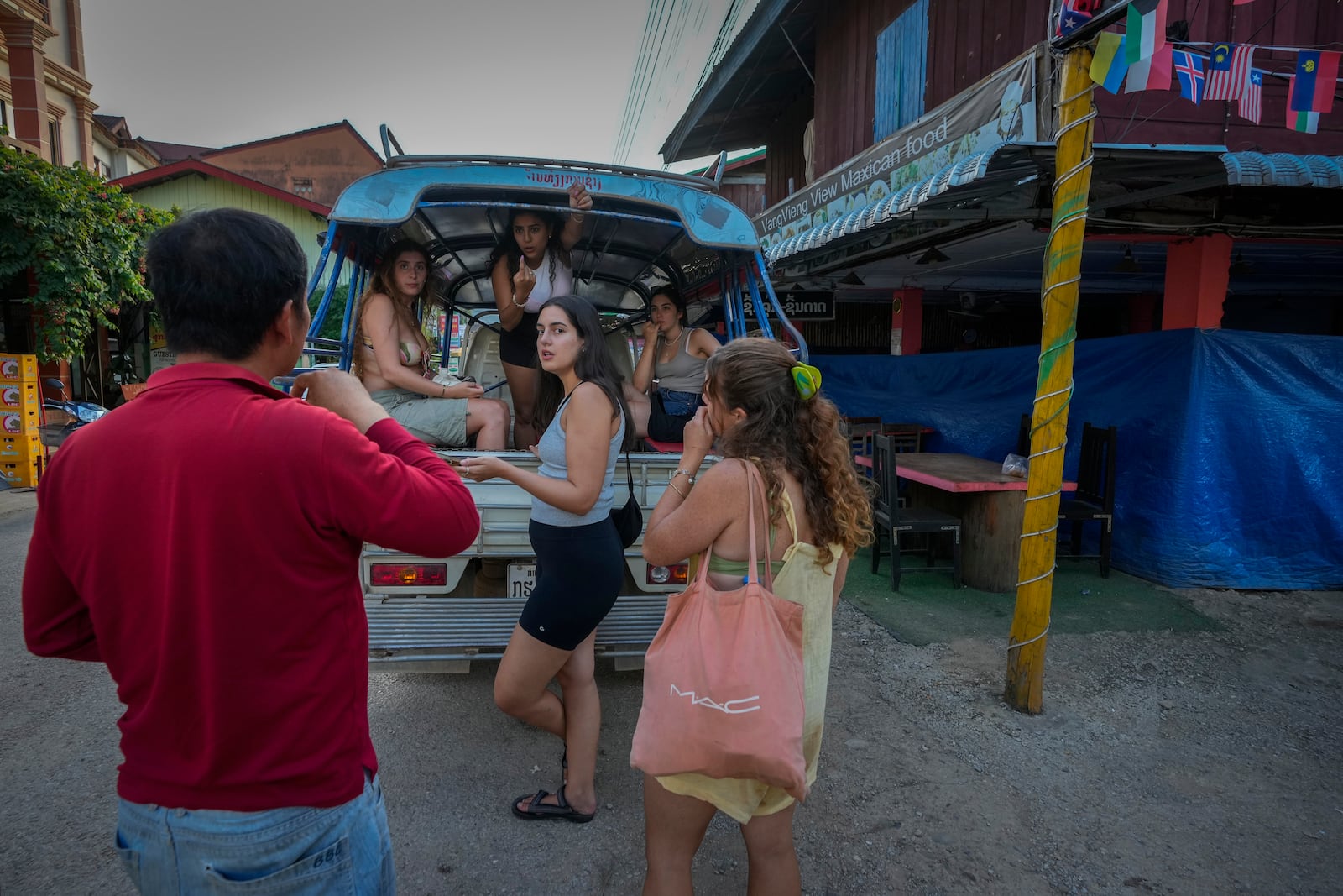 Tourists talk to a bar owner in Vang Vieng, Laos, Tuesday, Nov. 19, 2024. (AP Photo/Anupam Nath)