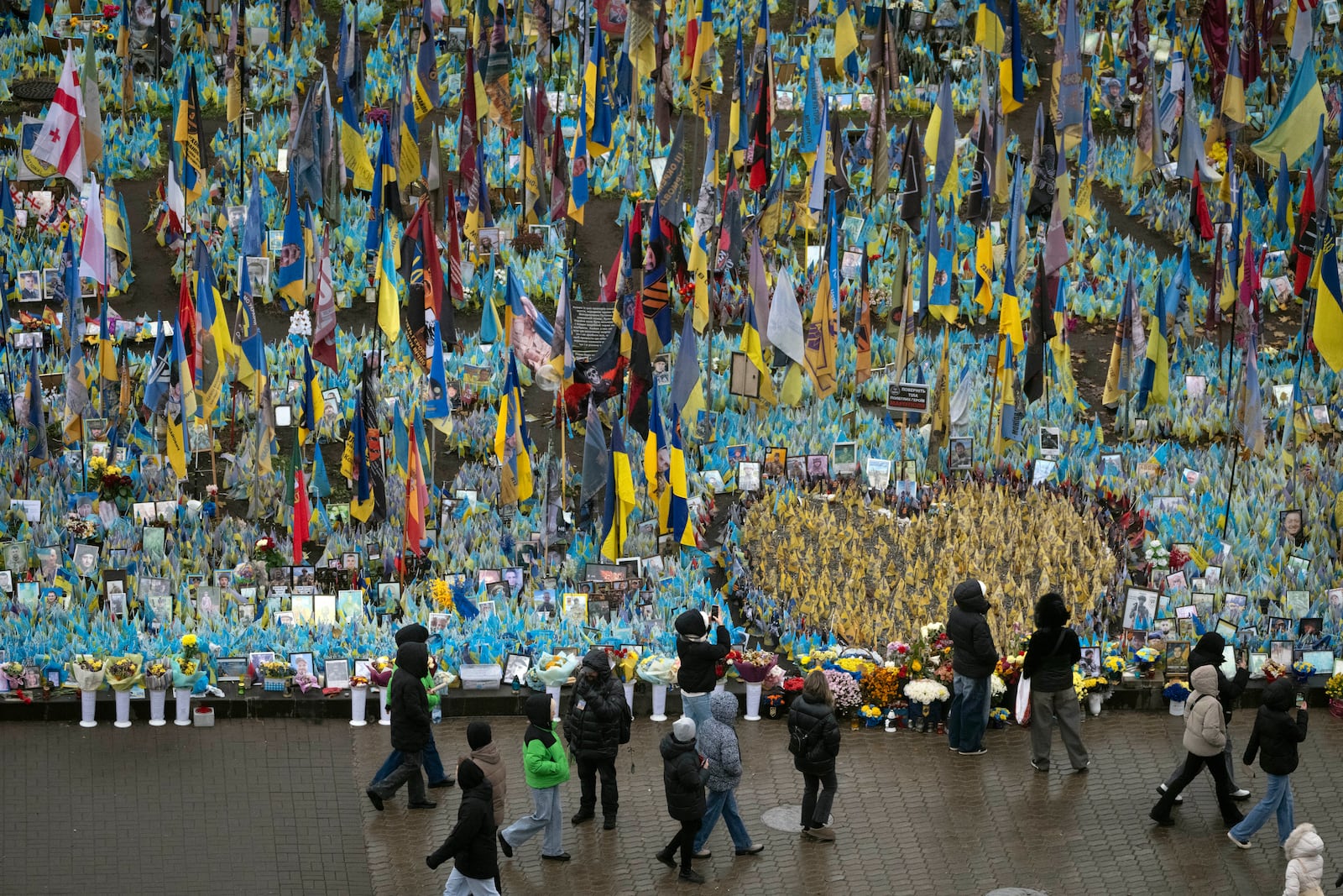 People walk past the memorial to fallen soldiers in Independence Square in Kyiv, Ukraine, Friday, Nov. 15, 2024. (AP Photo/Efrem Lukatsky)