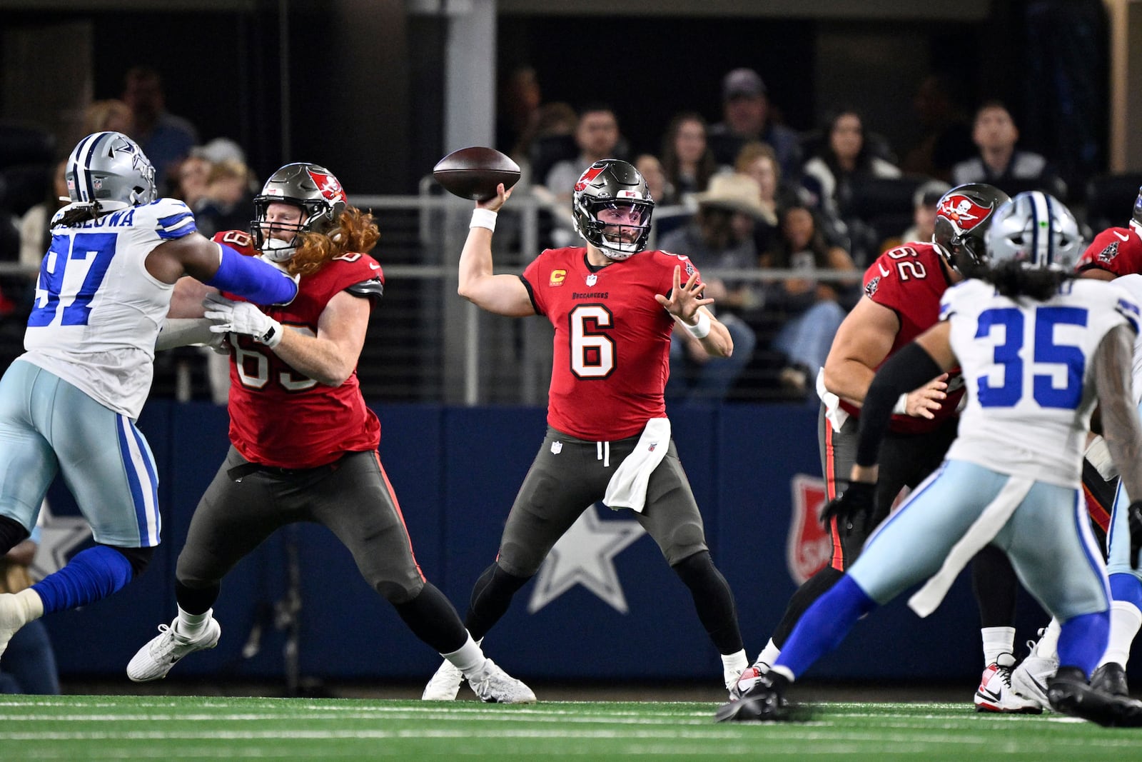 Tampa Bay Buccaneers quarterback Baker Mayfield throws form the pocket in the first half of an NFL football game as Dallas Cowboys' Osa Odighizuwan (97) and Marist Liufau (35) pressure in Arlington, Texas, Sunday, Dec. 22, 2024. (AP Photo/Jerome Miron)