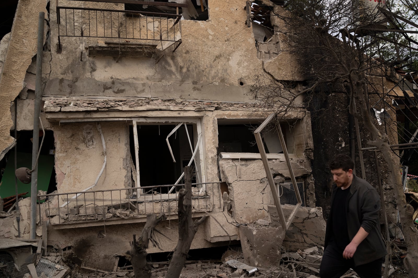 A man walks past a damaged building after a rocket fired from Lebanon hit an area in Rinatya, outskirts of Tel Aviv, Israel, Sunday, Nov. 24, 2024. (AP Photo/Leo Correa)