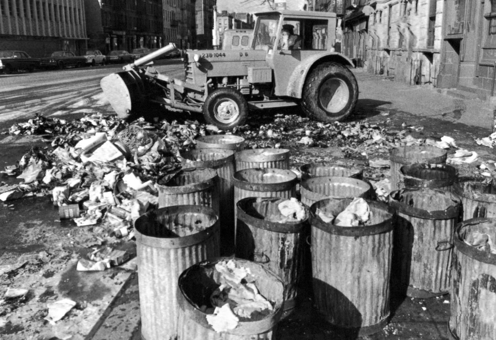 FILE - Empty garbage cans sit on a Harlem street in the Manhattan borough of New York, Feb. 11, 1968, as a sanitation worker removes the last of a mountain of refuse after a sanitation strike. (AP File Photo)