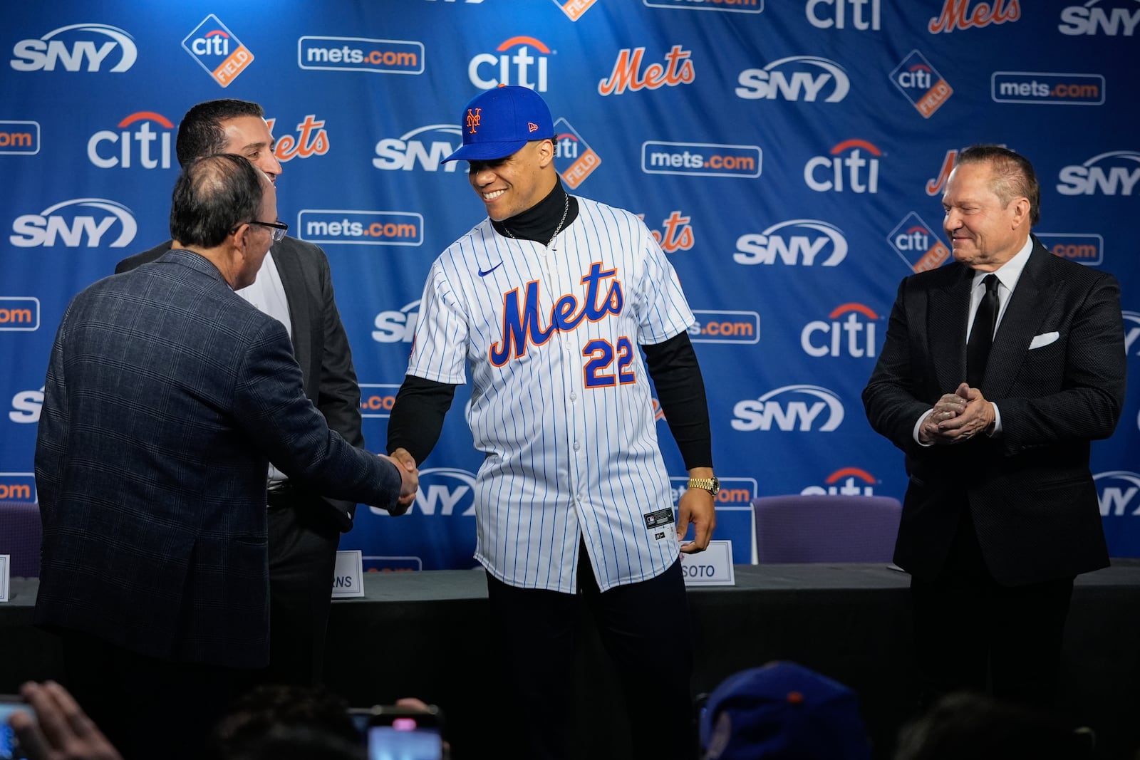 New York Mets owner Steven Cohen, left, shakes hands with Juan Soto, center, as sports agent Scott Boras, right and Mets president of baseball operations David Stearns, look on during a news conference, Thursday, Dec. 12, 2024, in New York. (AP Photo/Frank Franklin II)