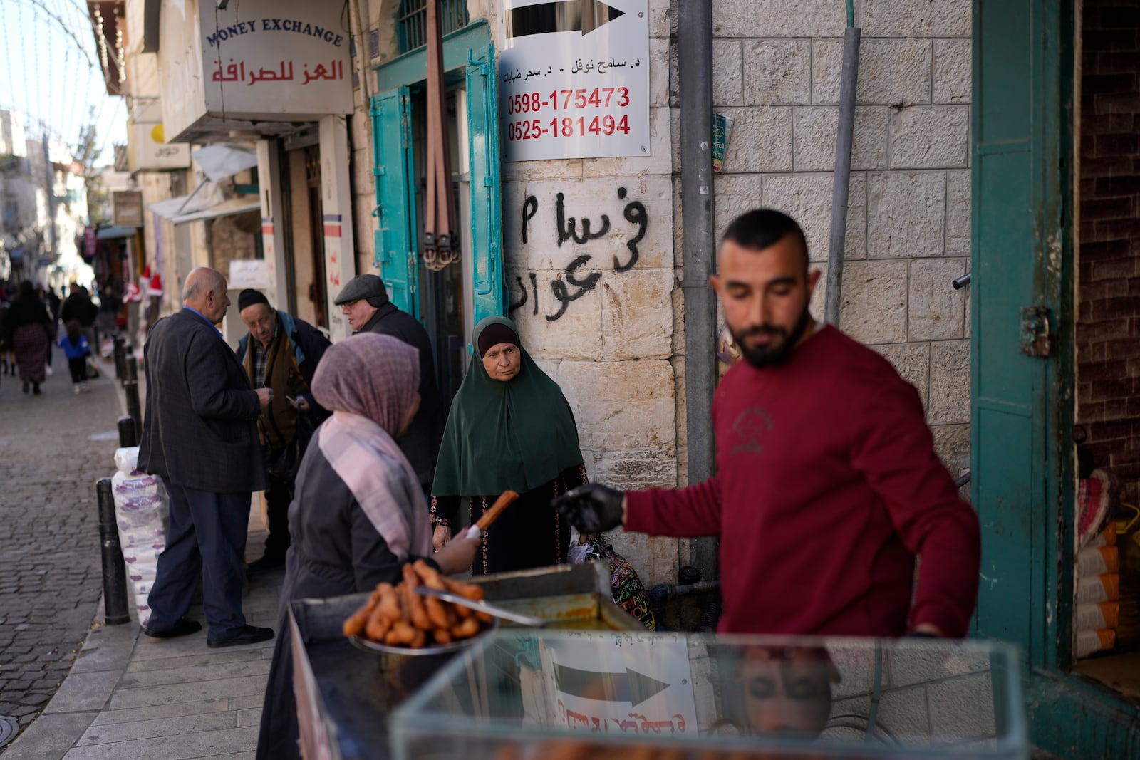 A woman buys street food near the Church of the Nativity, traditionally believed to be the birthplace of Jesus, on Christmas Eve, in the West Bank city of Bethlehem, Tuesday, Dec. 24, 2024. (AP Photo/Matias Delacroix)