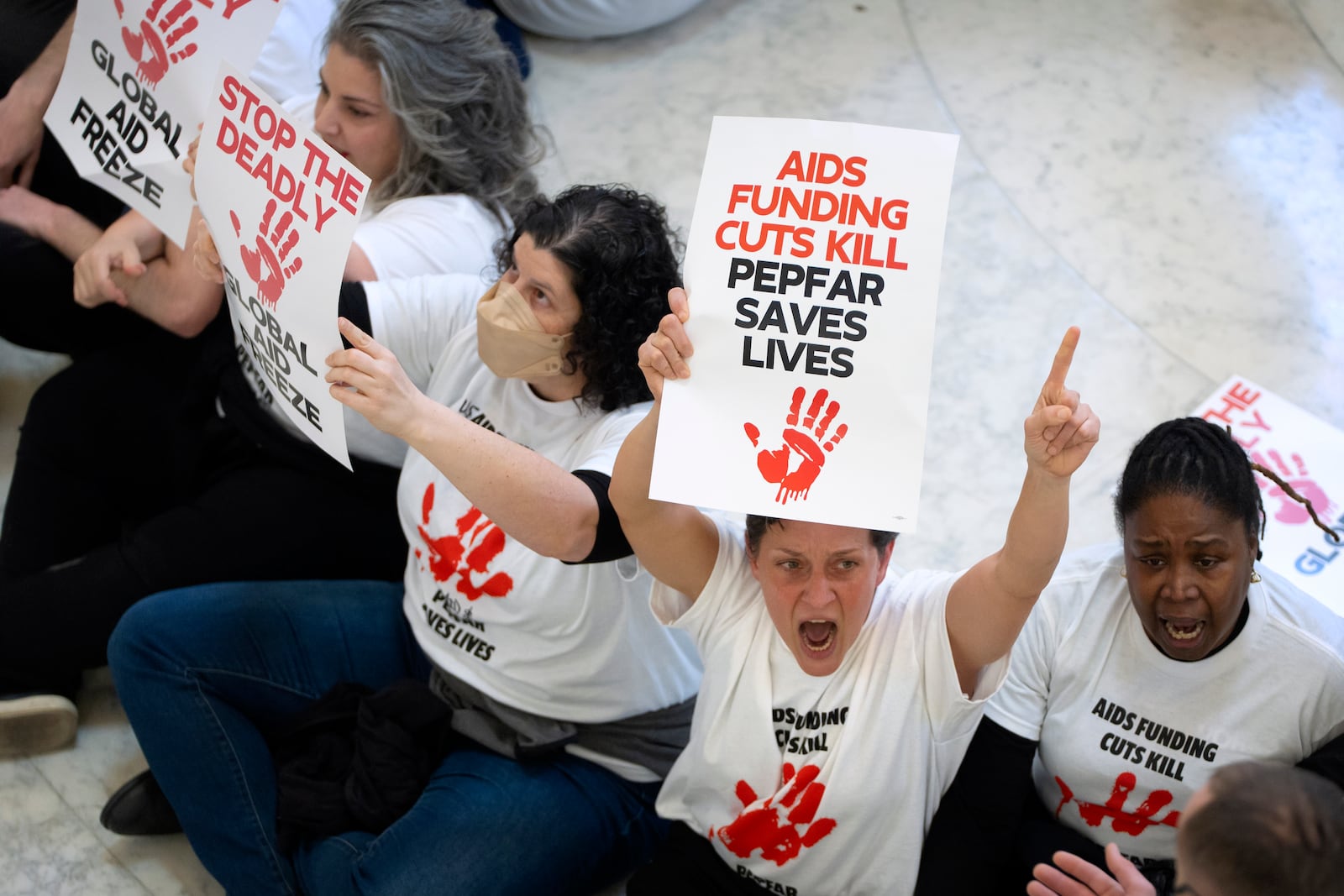 Demonstrators protest against cuts to American foreign aid spending, including USAID and the PEPFAR program to combat HIV/AIDS, at the Cannon House Office Building on Capitol Hill, Wednesday, Feb. 26, 2025, in Washington. (AP Photo/Mark Schiefelbein)