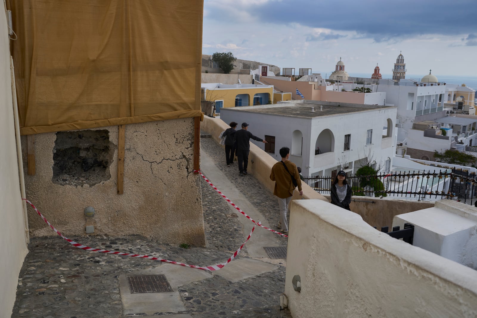 Tourists walk on the narrow streets of Fira town as emergency crews were deployed after an earthquake swarm worries Greek experts on the popular Aegean Sea holiday island of Santorini, southern Greece, Monday, Feb. 3, 2025. (AP Photo/Petros Giannakouris)