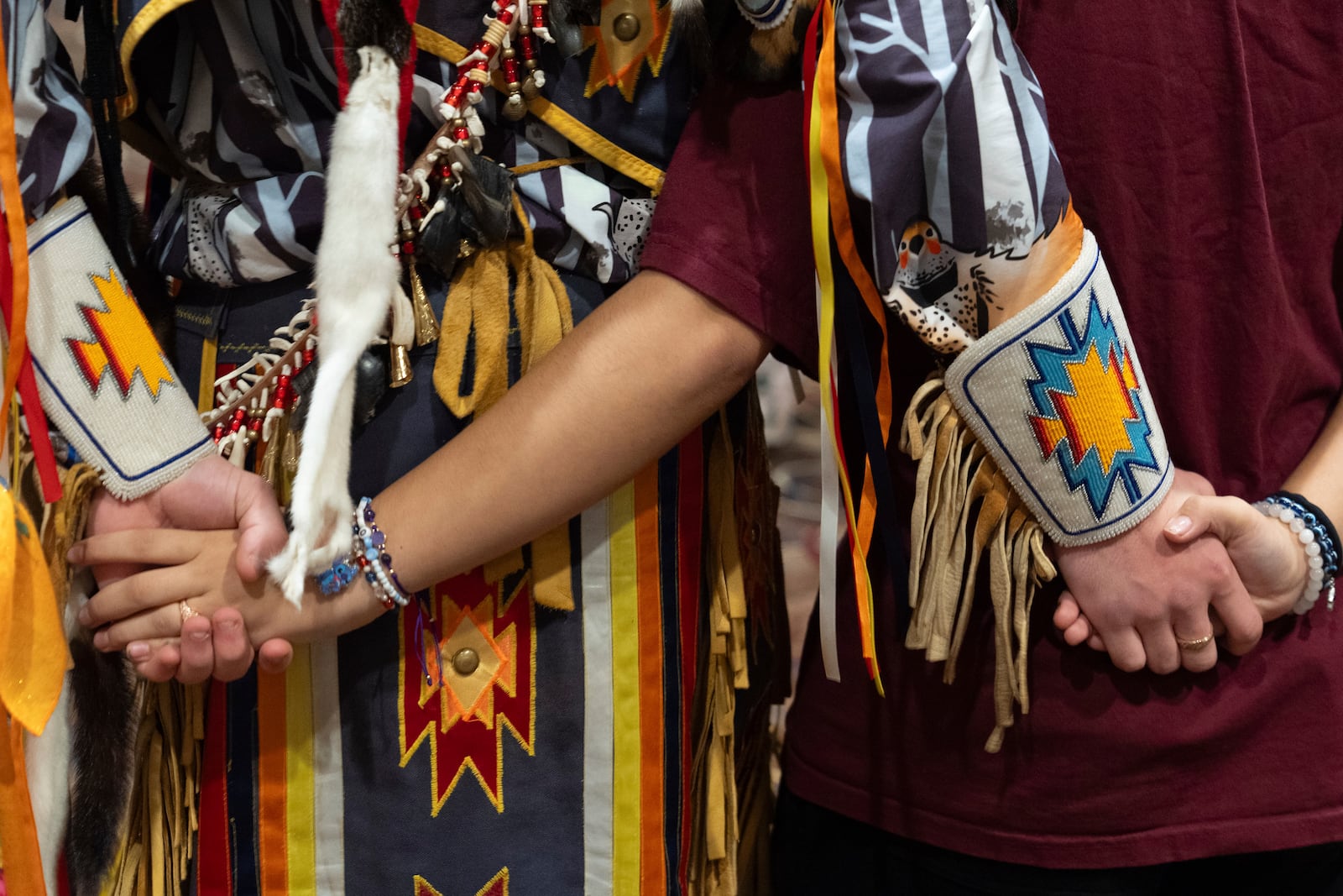 People hold hands during a dance at a powwow at Chinook Winds Casino Resort, Saturday, Nov. 16, 2024, in Lincoln City, Ore. (AP Photo/Jenny Kane)