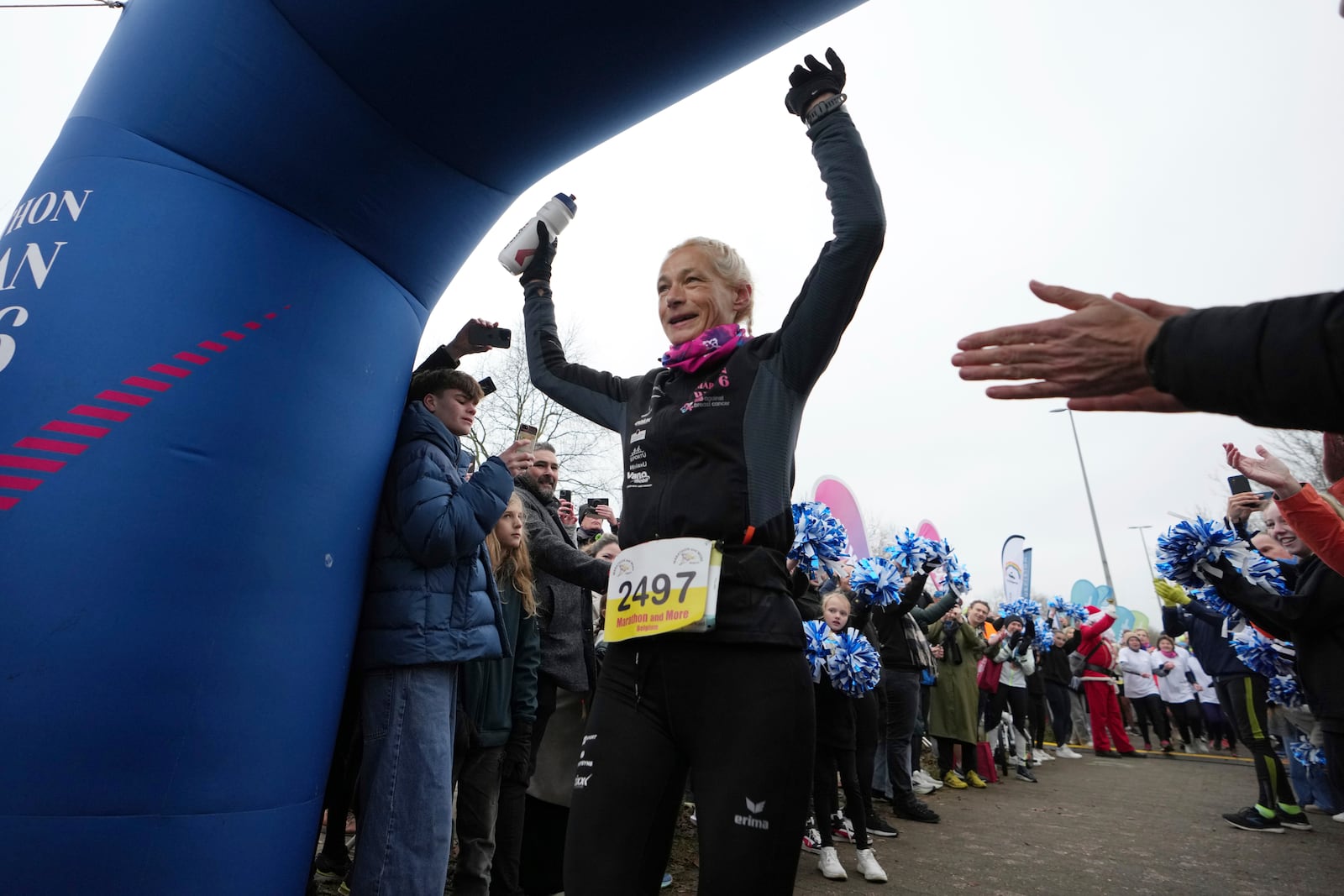 Belgian ultra runner Hilde Dosogne, center, is cheered on as she crosses the finish line during her 366th consecutive marathon in Ghent, Belgium, Tuesday, Dec. 31, 2024. (AP Photo/Virginia Mayo)