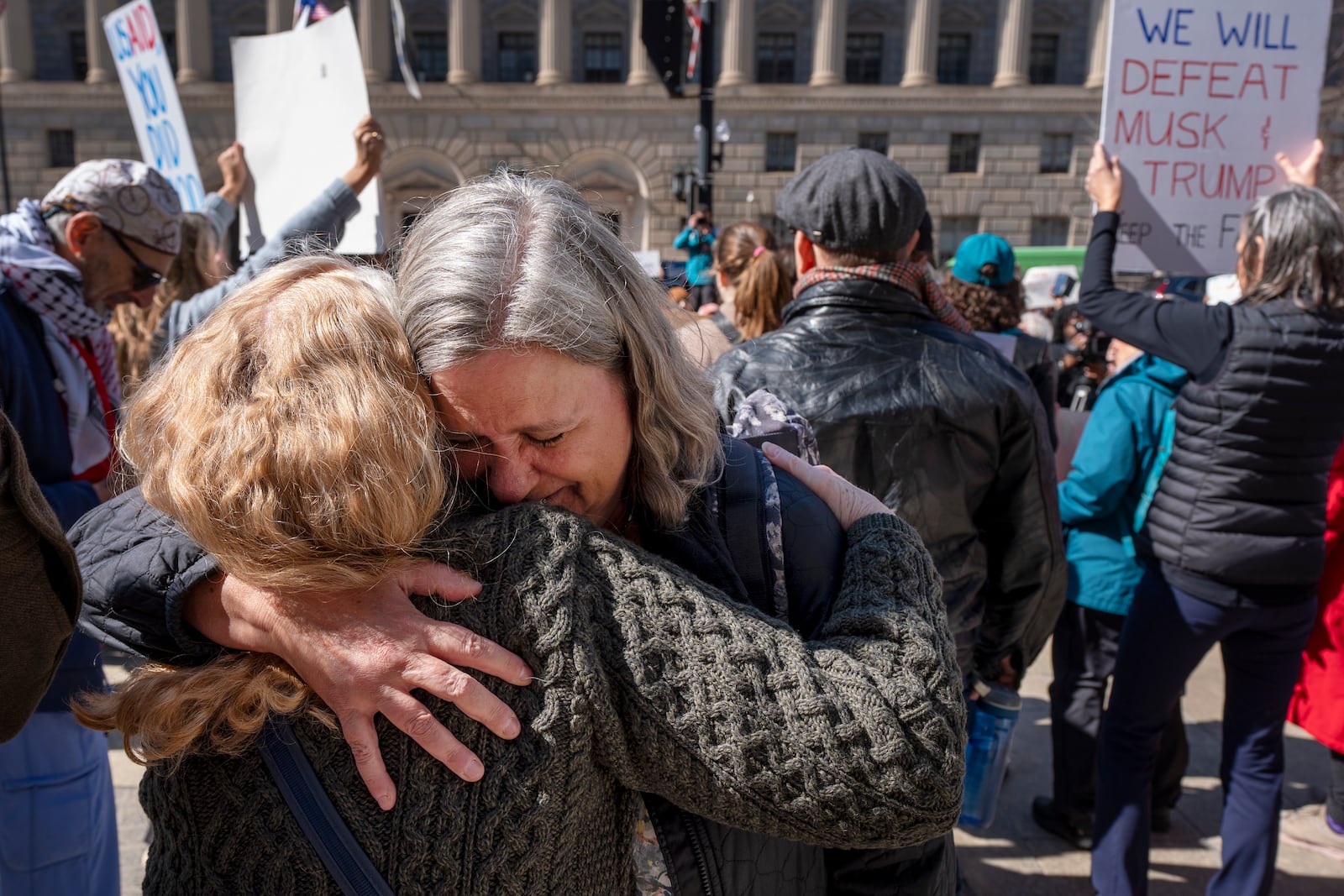 Lane Pollack, center, of Rockville, Md., a senior learning advisor at USAID for 14 years, is consoled by a co-worker after having 15 minutes to clear out her belongings from the USAID headquarters, Friday, Feb. 28, 2025, in Washington. (AP Photo/Jacquelyn Martin)