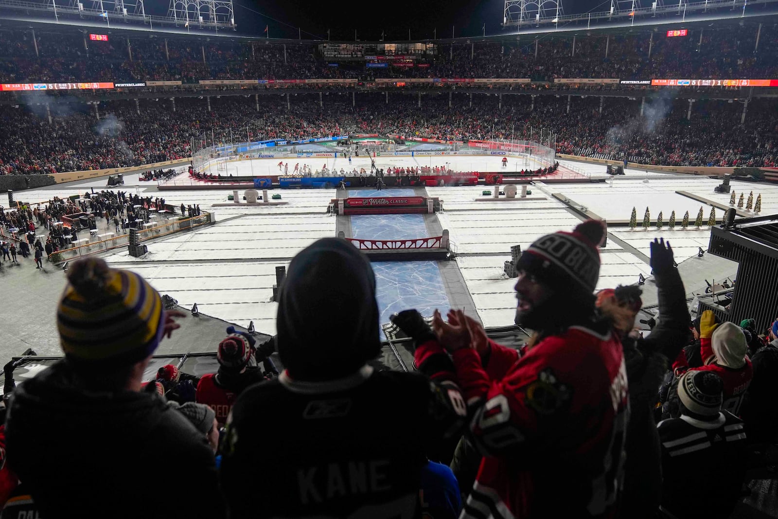 Fans celebrate after a goal by the Chicago Blackhawks against the St. Louis Blues during the third period of the NHL Winter Classic outdoor hockey game at Wrigley Field, Tuesday, Dec. 31, 2024, in Chicago. (AP Photo/Erin Hooley)