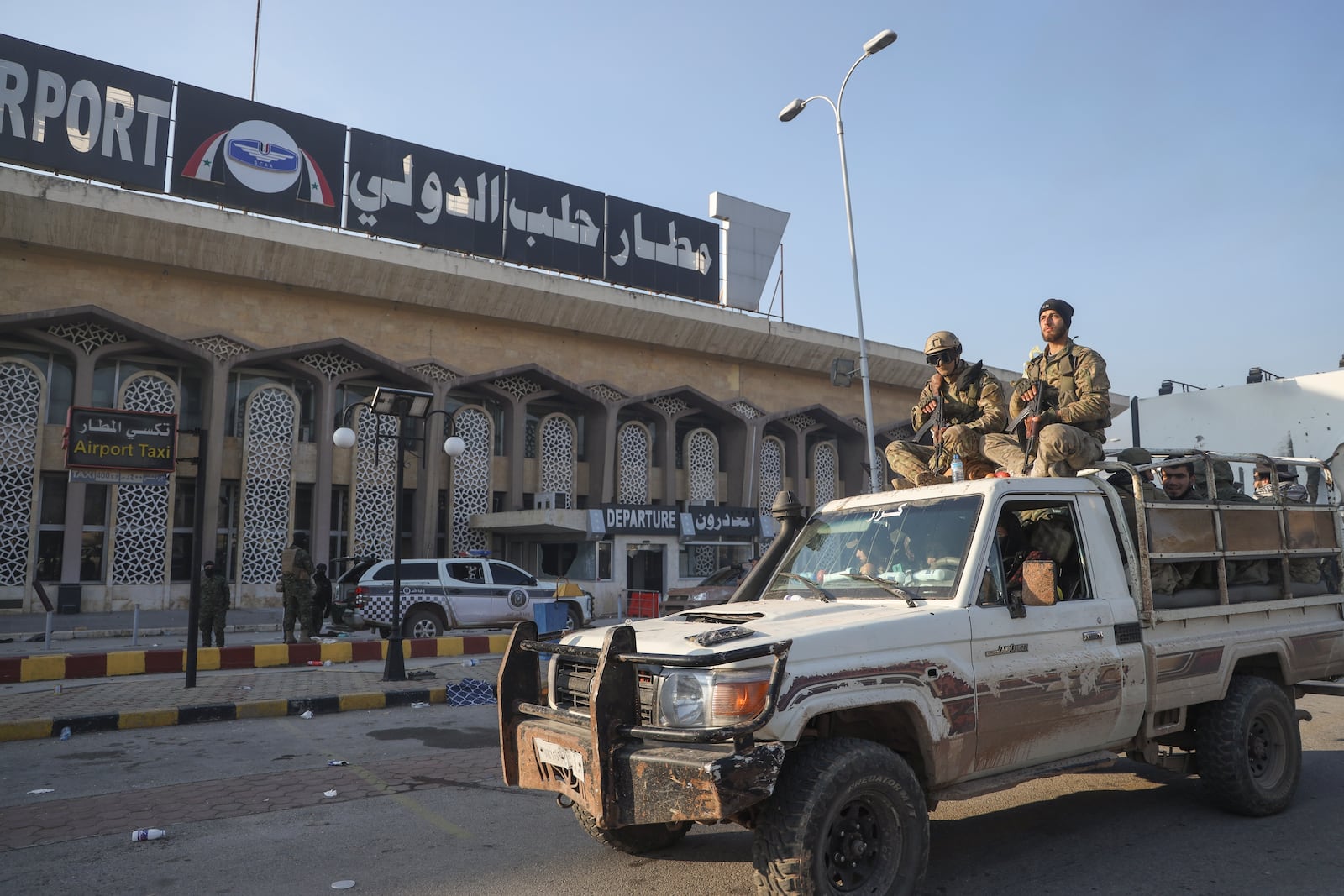 Syrian opposition fighters ride on a pick-up truck at the Aleppo international airpot in Aleppo Monday, Dec. 2, 2024. .(AP Photo/Omar Albam)