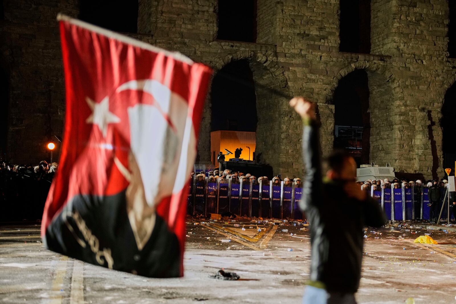 A man holds a Turkish flag with the image of Turkey's founding father Mustafa Kemal Ataturk in front of anti riot police officers during a protest against the arrest of Istanbul's Mayor Ekrem Imamoglu in Istanbul, Turkey, Friday, March 21, 2025. (AP Photo/Emrah Gurel)