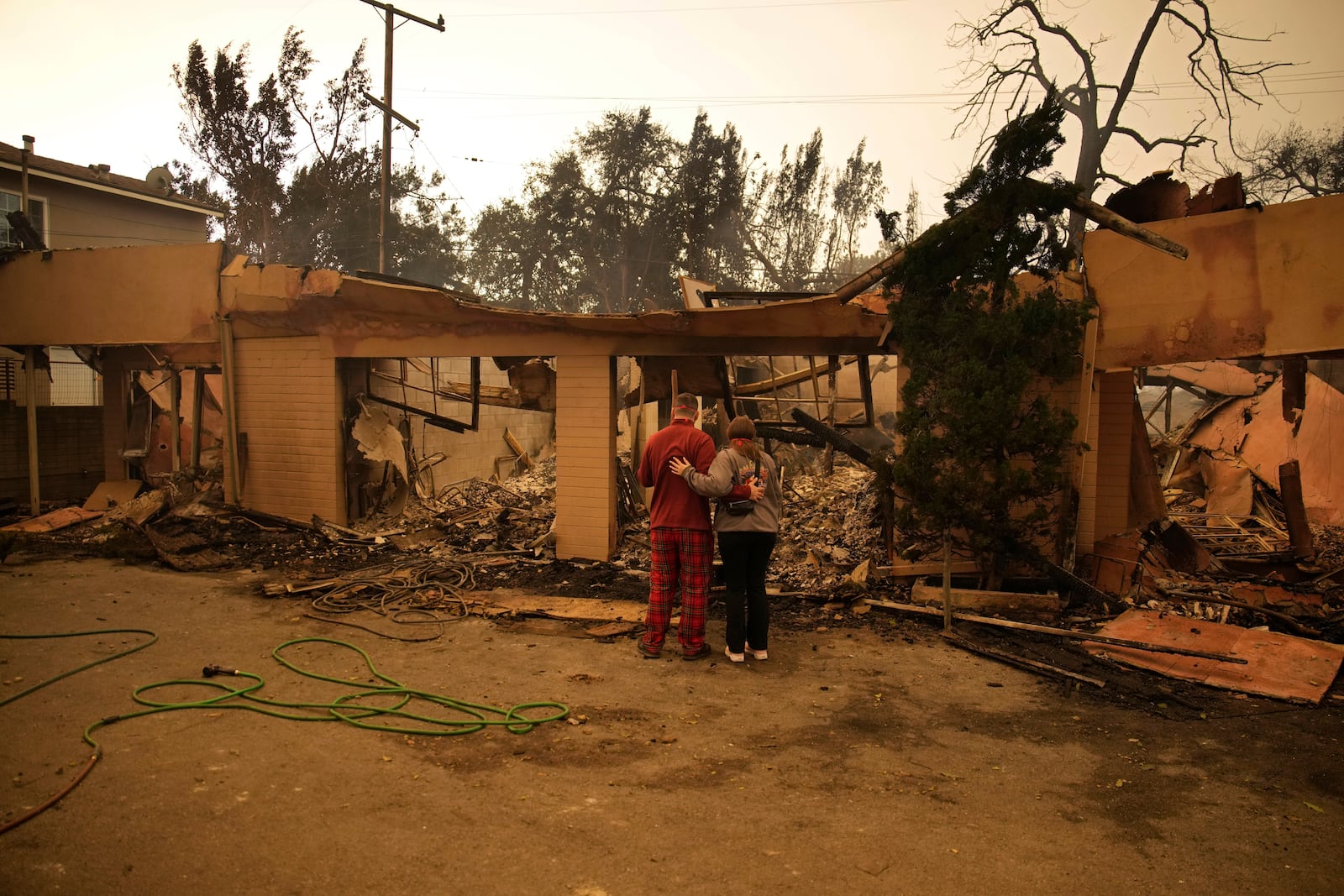 Shane Torre, left, and Stephanie Rodriguez embrace as the look at what remains of their home destroyed by the Eaton Fire on Thursday, Jan. 9, 2025, in Altadena, Calif. (AP Photo/John Locher)