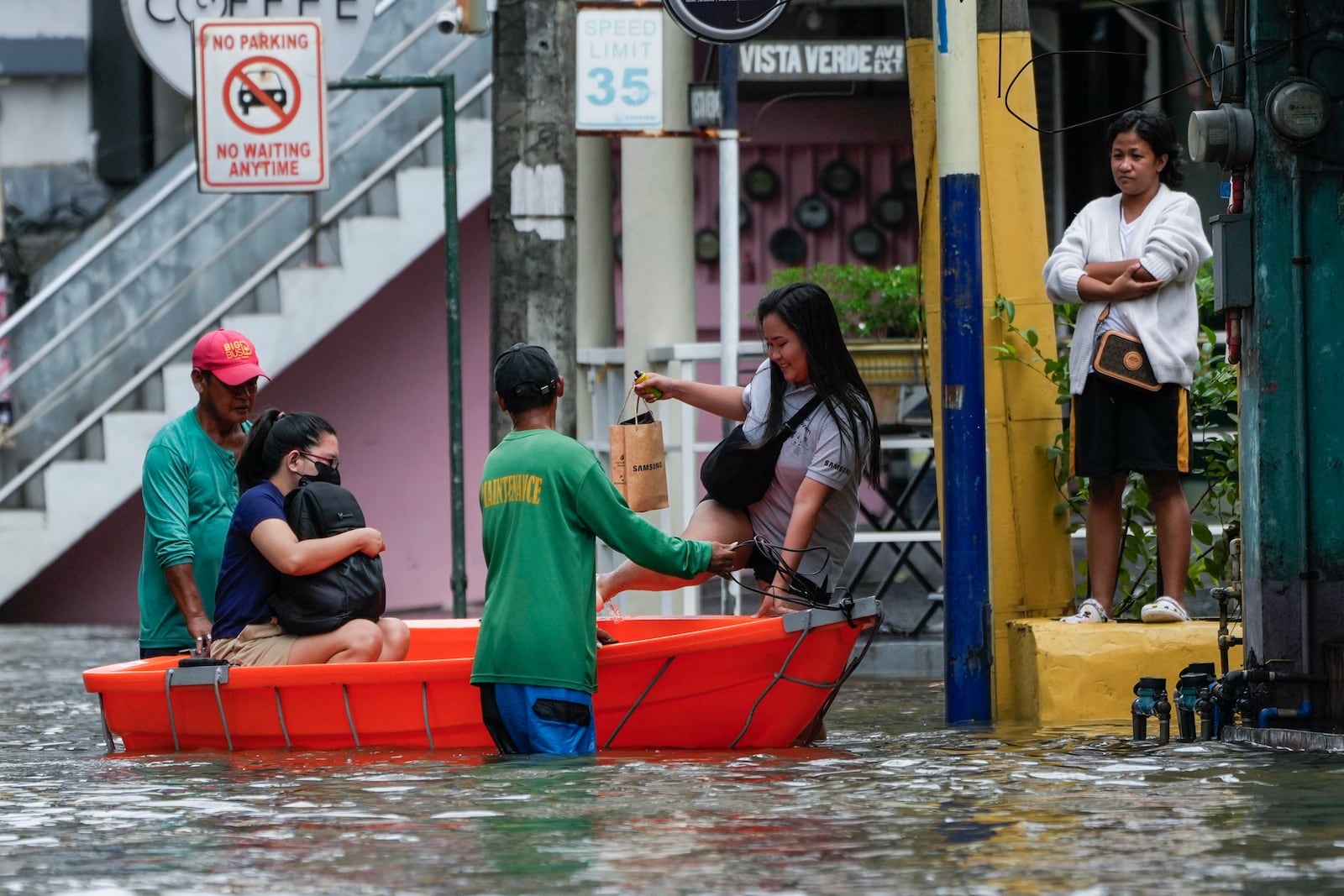 Residents use a boat to cross flooded streets caused by Tropical Storm Trami on Friday, Oct. 25, 2024, in Cainta, Rizal province, Philippines. (AP Photo/Aaron Favila)