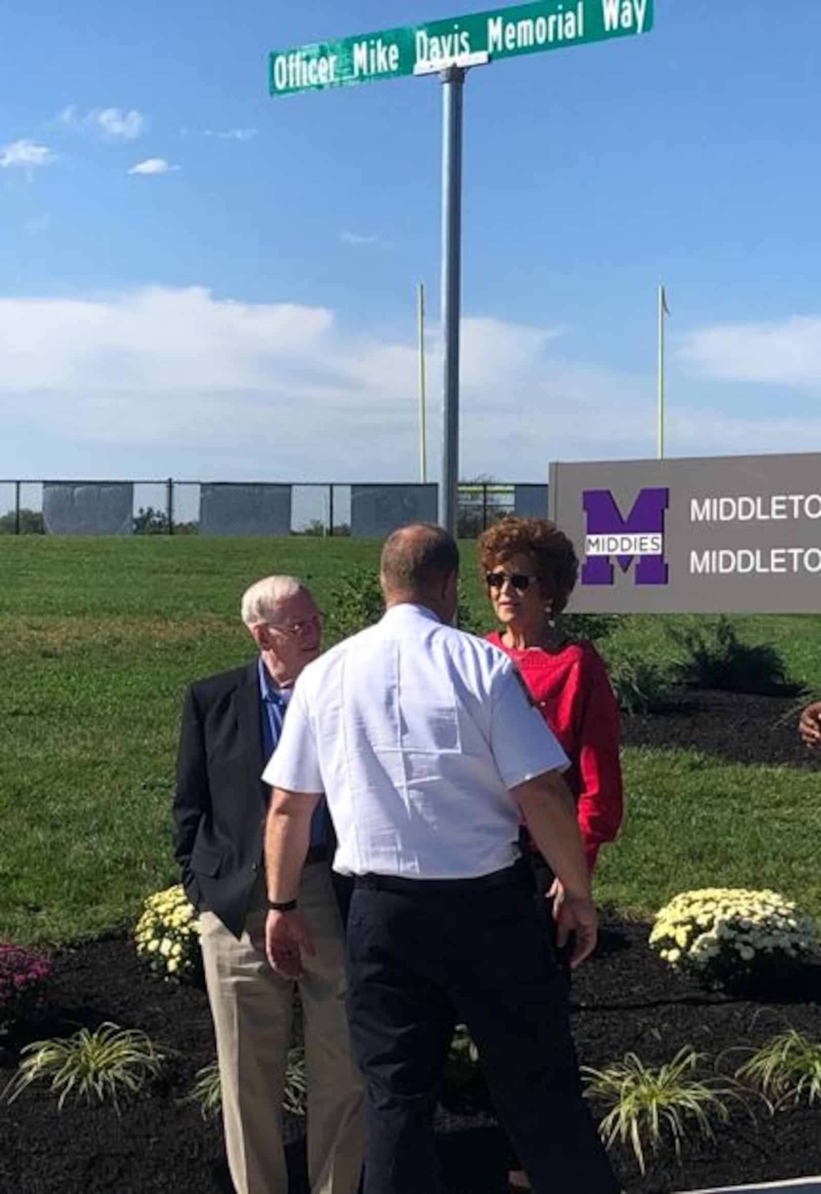 Bev Davis, who was married to Middletown police officer Mike Davis for 27 years, talks with Ernie Howard and police Chief David Birk Wednesday during an unveiling of the Officer Mike Davis Memorial Way sign. RICK McCRABB/STAFF