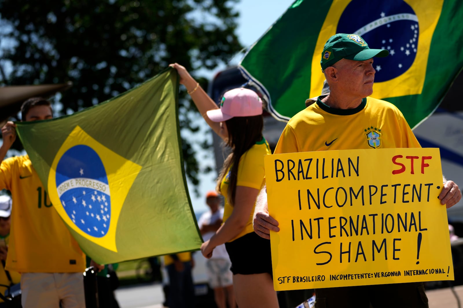 Supporters of former President Jair Bolsonaro hold up posters and flags in support of a proposed bill to grant amnesty to those arrested for storming government buildings in an alleged coup attempt in 2023, in Brasilia, Brazil, Sunday, March 16, 2025. (AP Photo/Eraldo Peres)