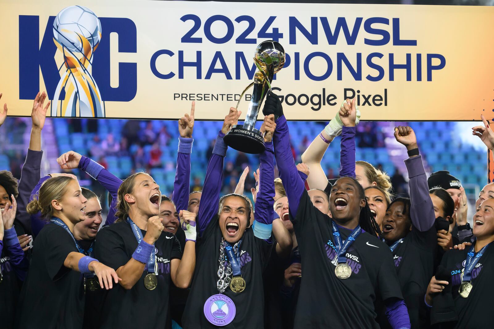 Orlando Pride forwards Marta, center, and Barbra Banda, right, lift the NWSL championship trophy together after defeating the Washington Spirit in an NWSL soccer game, Saturday, Nov. 23, 2024, in Kansas City, Mo. (AP Photo/Reed Hoffmann)