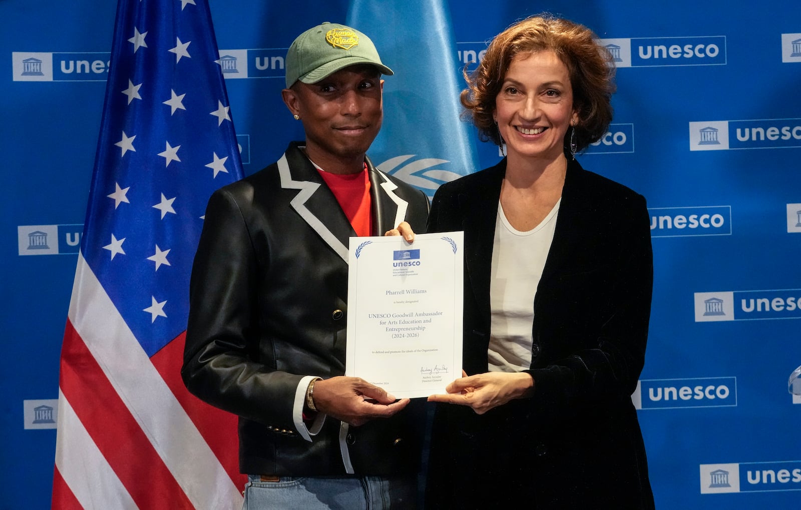 Pharrell Williams, left, holds his diploma of Goodwill Ambassador for for Arts, Education and Entrepreneurship as he poses with UNESCO Director General Audrey Azoulay at UNESCO headquarters in Paris, Tuesday, Dec. 17, 2024. (AP Photo/Michel Euler)