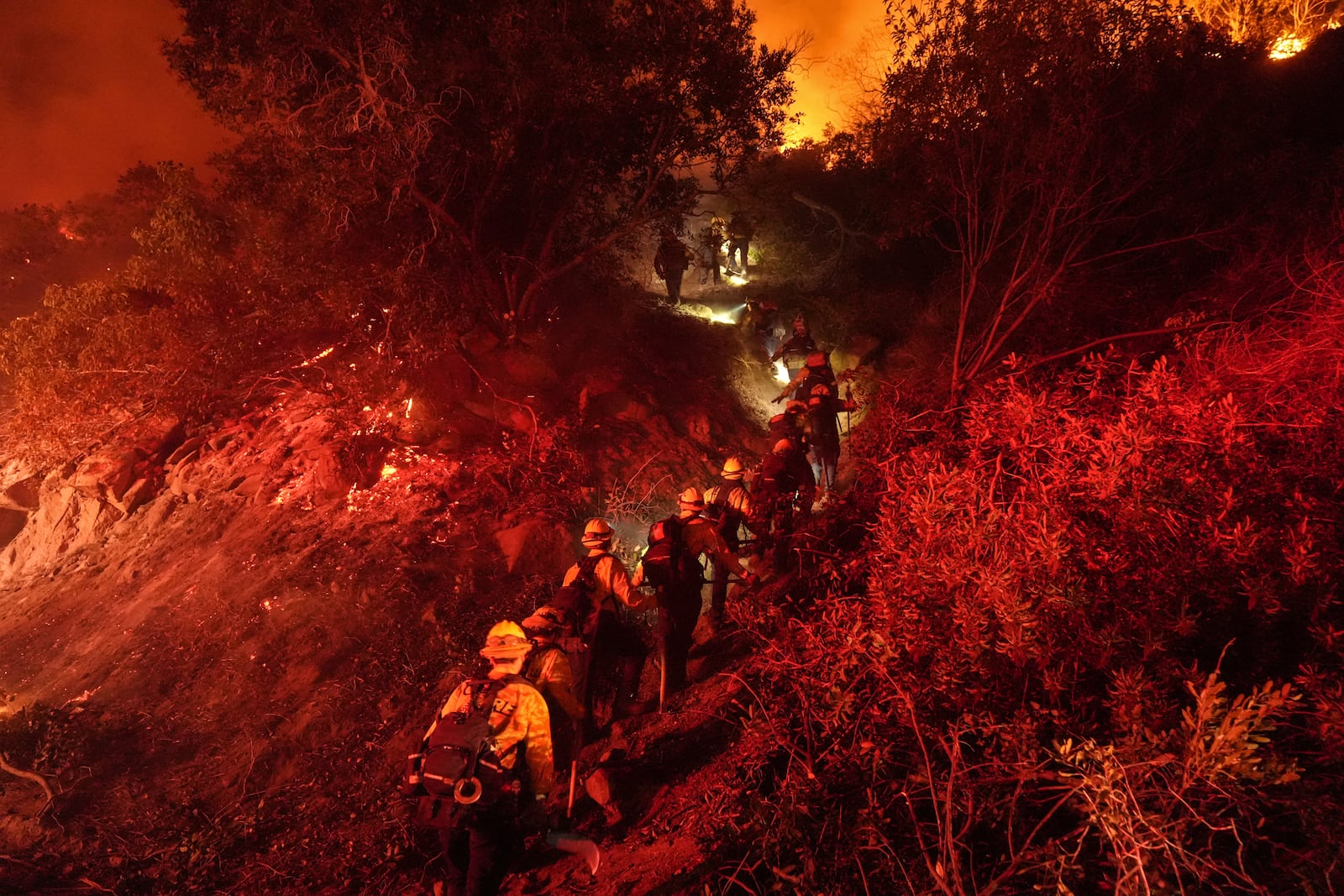 Firefighters walk up a ridge to battle the Lilac Fire in Bonsall, Calif., Tuesday, Jan. 21, 2025. (AP Photo/Jae C. Hong)