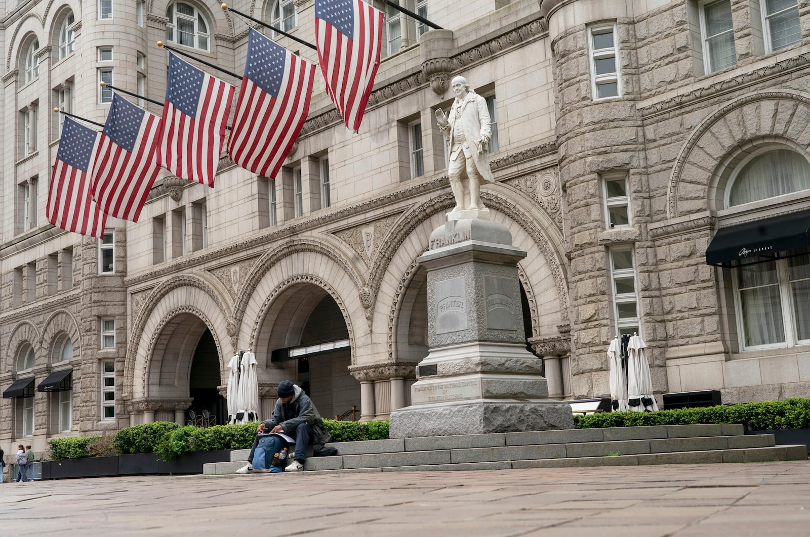 FILE - A man sits by Old Post Office building, May 12, 2022, in Washington. (AP Photo/Gemunu Amarasinghe)