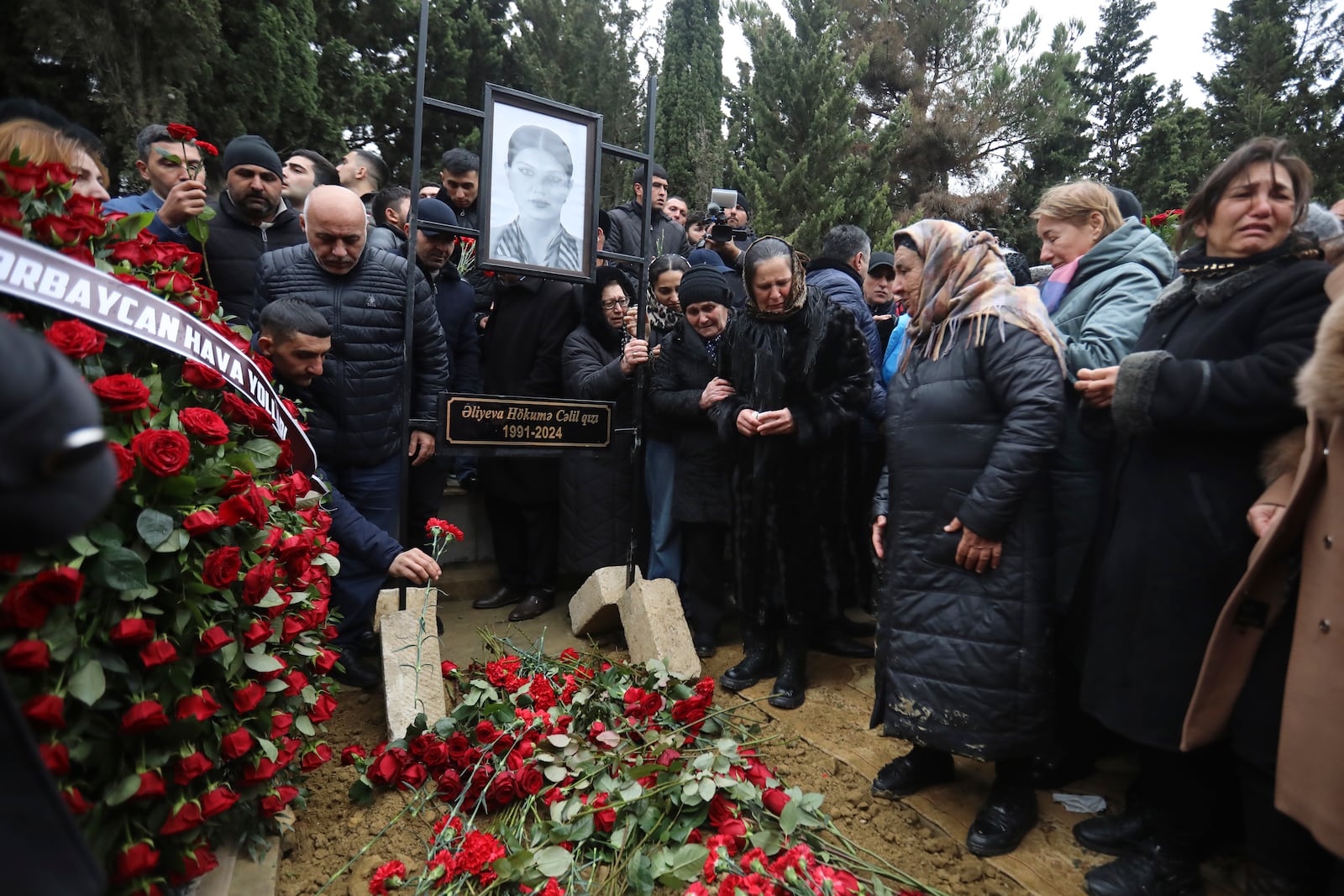 People mourn at the grave of flight attendant Hokume Aliyeva during a funeral of the crew members of the Azerbaijan Airlines Embraer 190 killed in a deadly plane crash in Kazakhstan this week, at the II Alley of Honor in Baku, Azerbaijan, Sunday, Dec. 29, 2024. (AP photo)