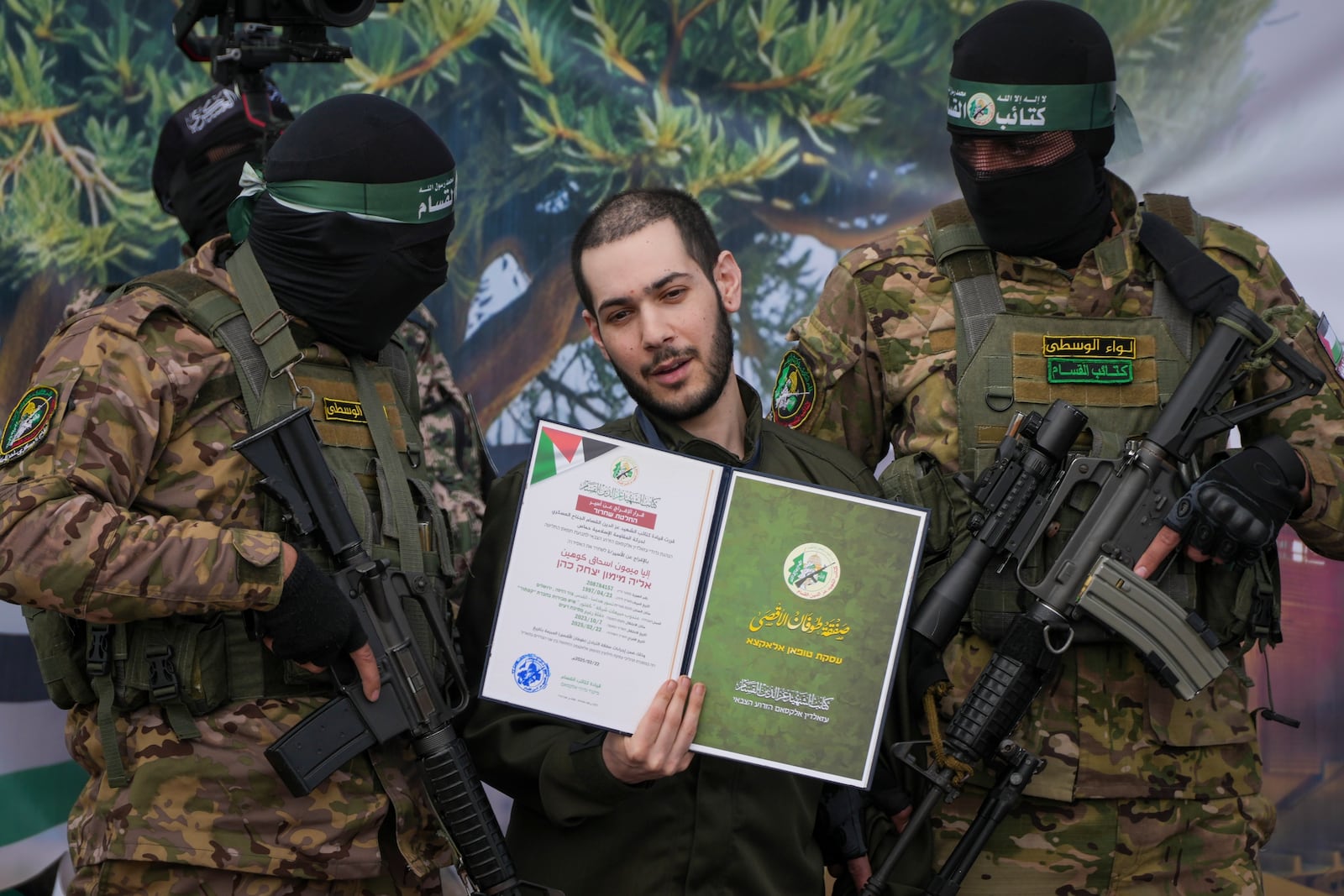 Israeli hostage Eliya Cohen, centre, is asked to show a Hamas issued certificate as he is escorted by militants before being handed over to the Red Cross in Nuseirat, central Gaza Strip, Saturday, Feb. 22, 2025. (AP Photo/Abdel Kareem Hana)