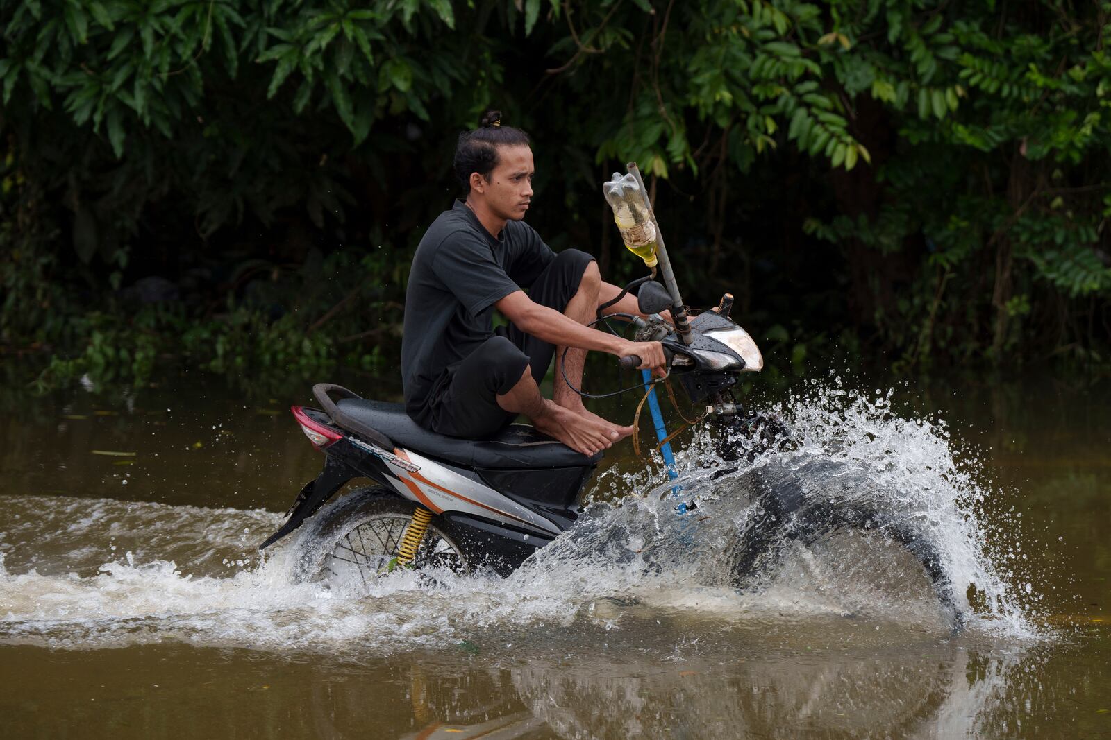 A residents rides a self modified motorcycle through a road covered by flood water in Tumpat, outskirts of Kota Bahru, Malaysia, Tuesday, Dec. 3, 2024. (AP Photo/Vincent Thian)