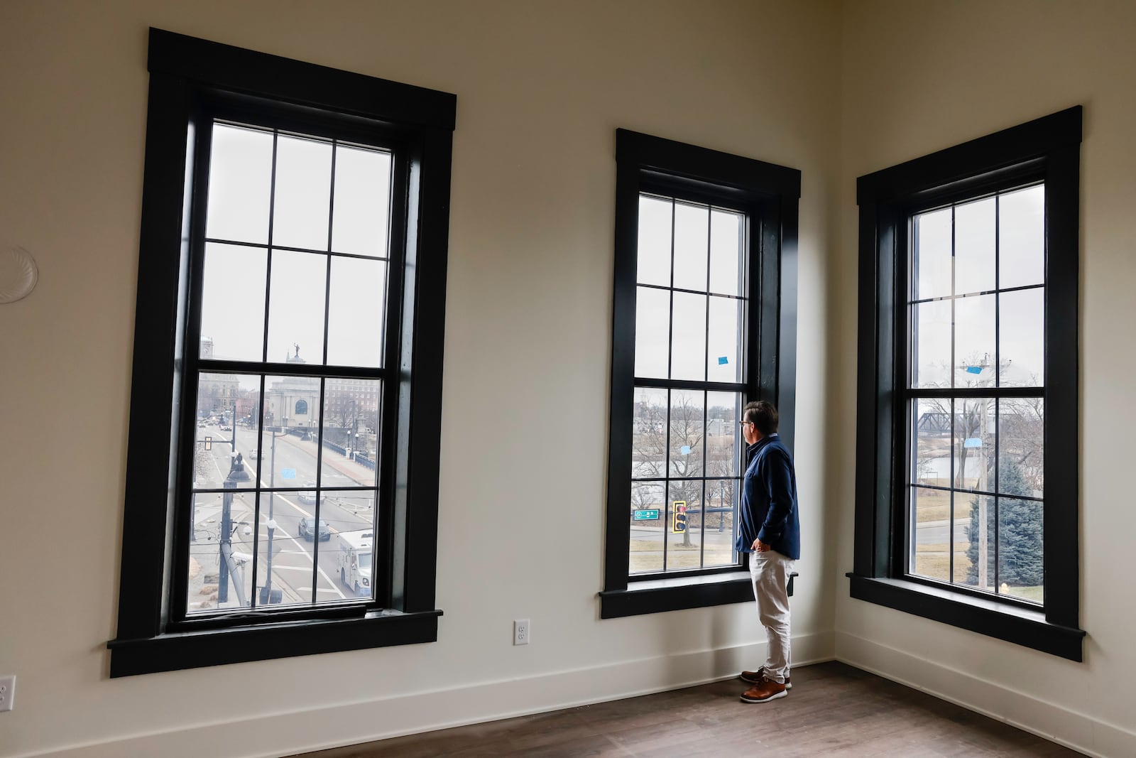 New one bedroom apartments are nearing completion on Main Street in Hamilton. The apartments have between 10- and 16-foot ceilings, open floor plans and large walk-in closet with laundry. Pictured is property owner John Stretch on Feb. 13, 2025, looking out one of the large windows overlooking downtown Hamilton. NICK GRAHAM/STAFF