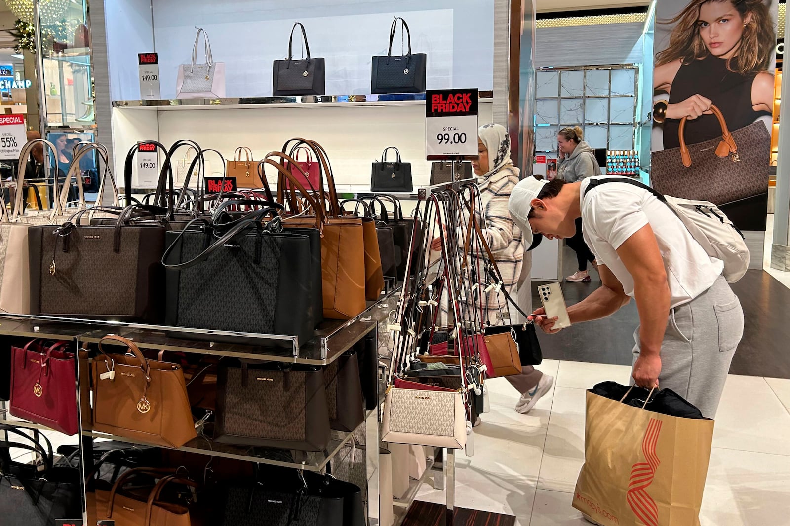 A shopper looks at handbags at Macy's department store on Sunday, Nov. 24, 2024, in New York. (AP Photo/Anne D'Innocenzio)