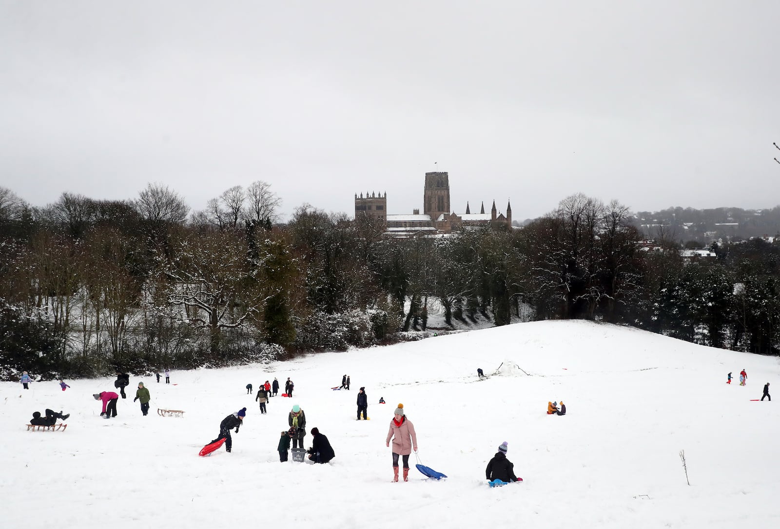 Members of the public are seen sledging on a hill with Durham Cathedral which is surrounded by heavy snow in Durham, North East England, as the severe weather continues across England, Sunday, Jan. 5, 2025. (AP Photo/Scott Heppell)