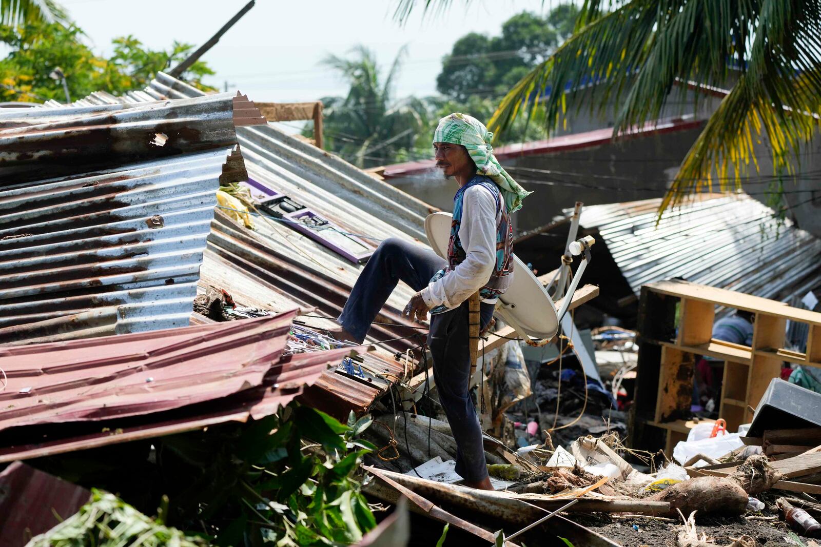 Residents try to recover belongings from their damaged homes after a recent landslide triggered by Tropical Storm Trami struck Talisay, Batangas province, Philippines leaving thousands homeless and several villagers dead on Saturday, Oct. 26, 2024. (AP Photo/Aaron Favila)