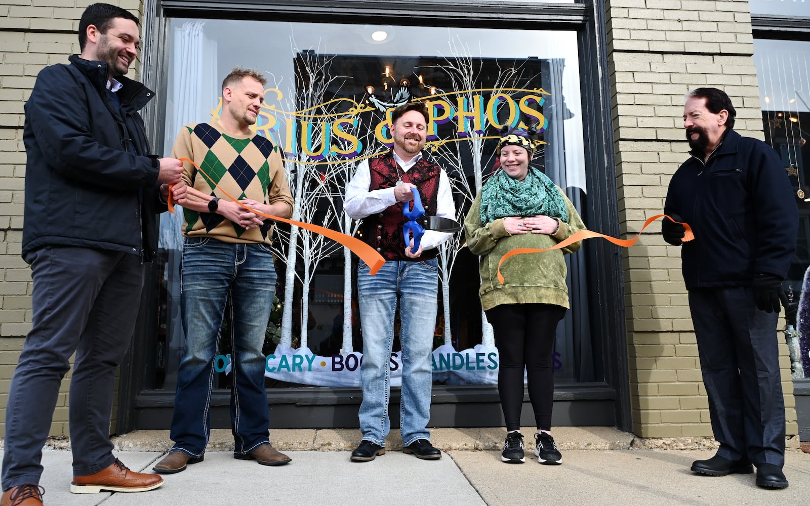 Arius and Phos, an apothecary and botanica sharing space inside Seraph by the River at 118 Main St. in Hamilton, is now open for business. Owner Isaac Reed said the store has everything for one's mystical needs, from teas and candles to tarot cards and books. Pictured is the ribbon cutting outside the shop on Monday, Dec. 2, 2024. MICHAEL D. PITMAN/STAFF