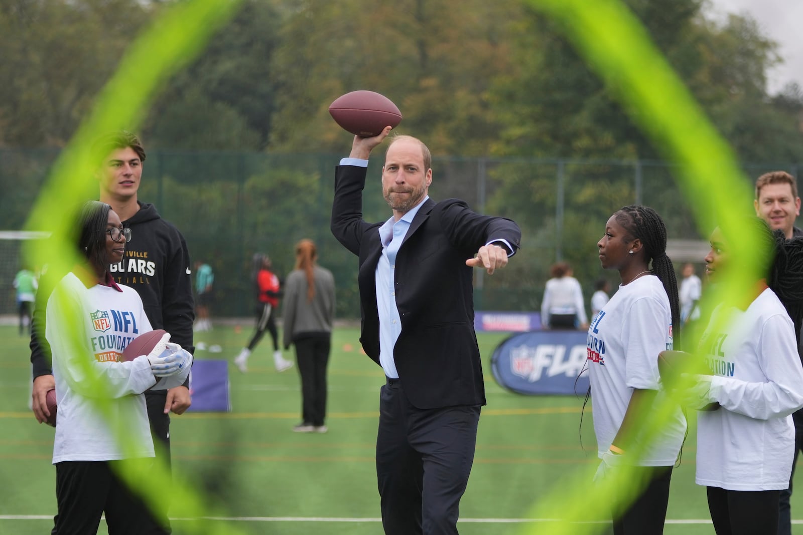 Britain's Prince William throws a football at a target, watched by Louis Rees-Zammit, left, as he attends a NFL Foundation NFL Flag event, an inclusive and fast paced American Football format, in London, Tuesday, Oct. 15, 2024. (AP Photo/Kin Cheung, Pool)