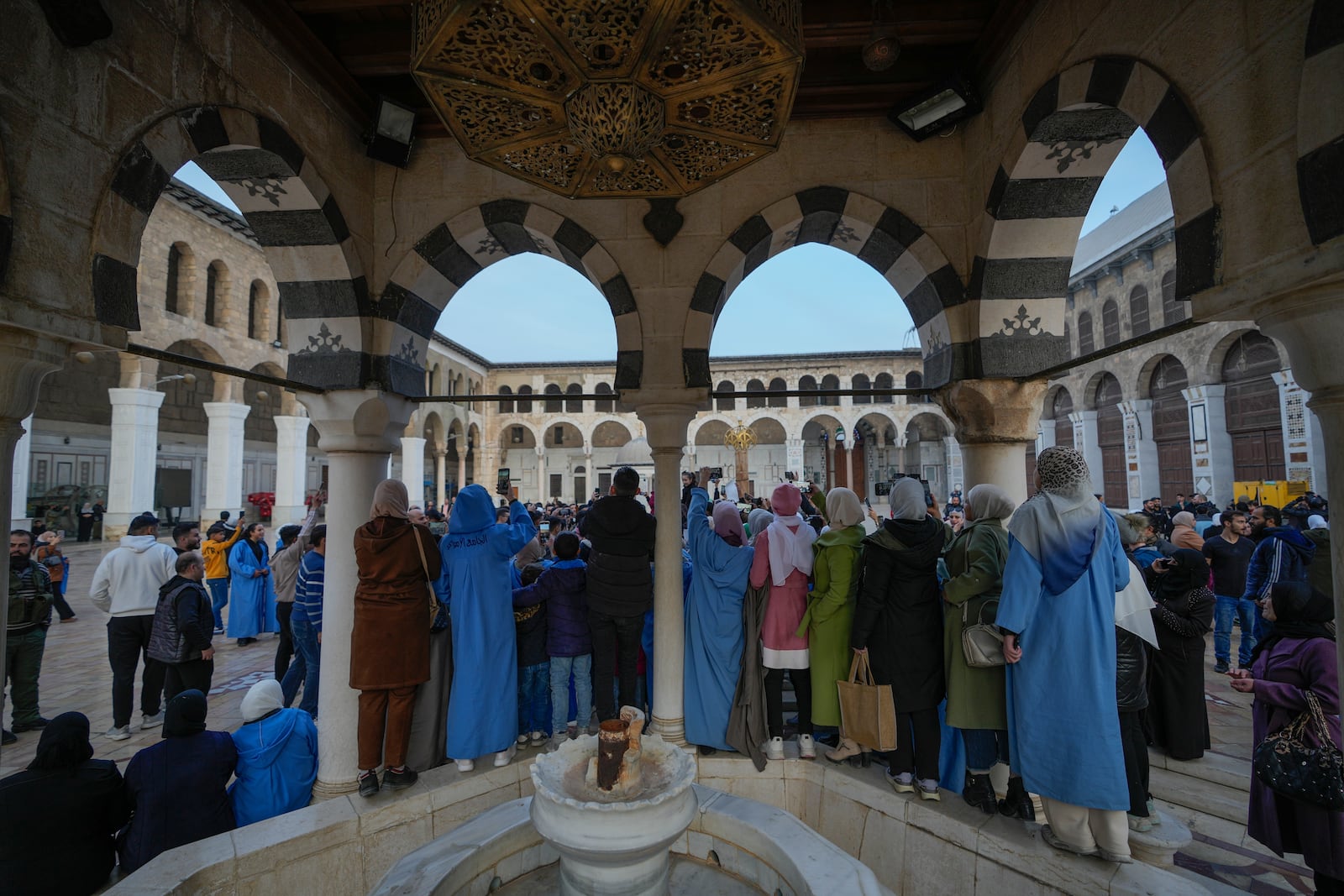 People watch and take photos with their cell phones as opposition supporters celebrate in the courtyard of the Umayyad Mosque in the old walled city of Damascus, Syria, on Tuesday, Dec. 10, 2024. (AP Photo/Hussein Malla)